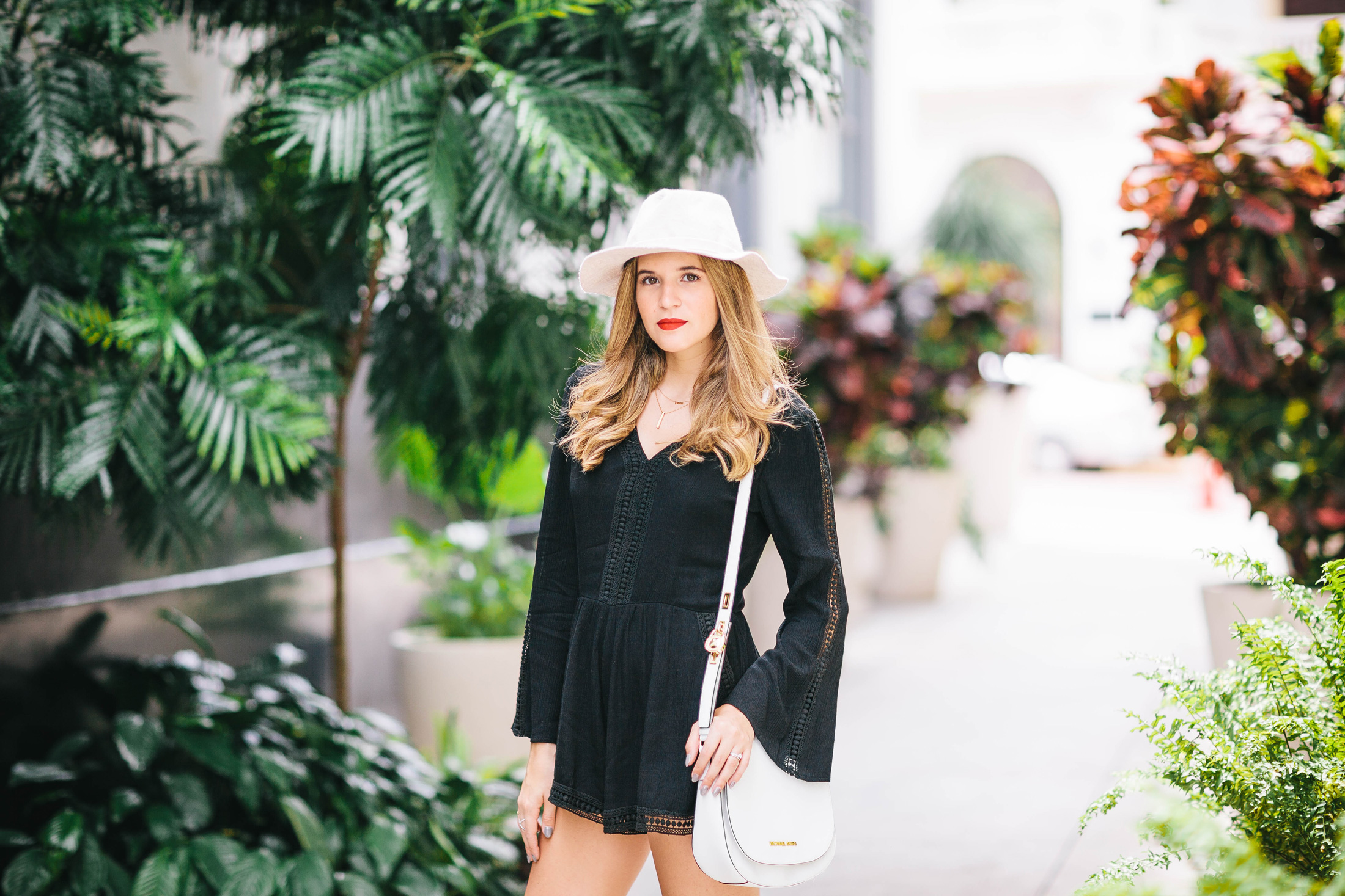 Blogger Maristella wears a black romper and beige hat with red lips in Casco Viejo, Panama