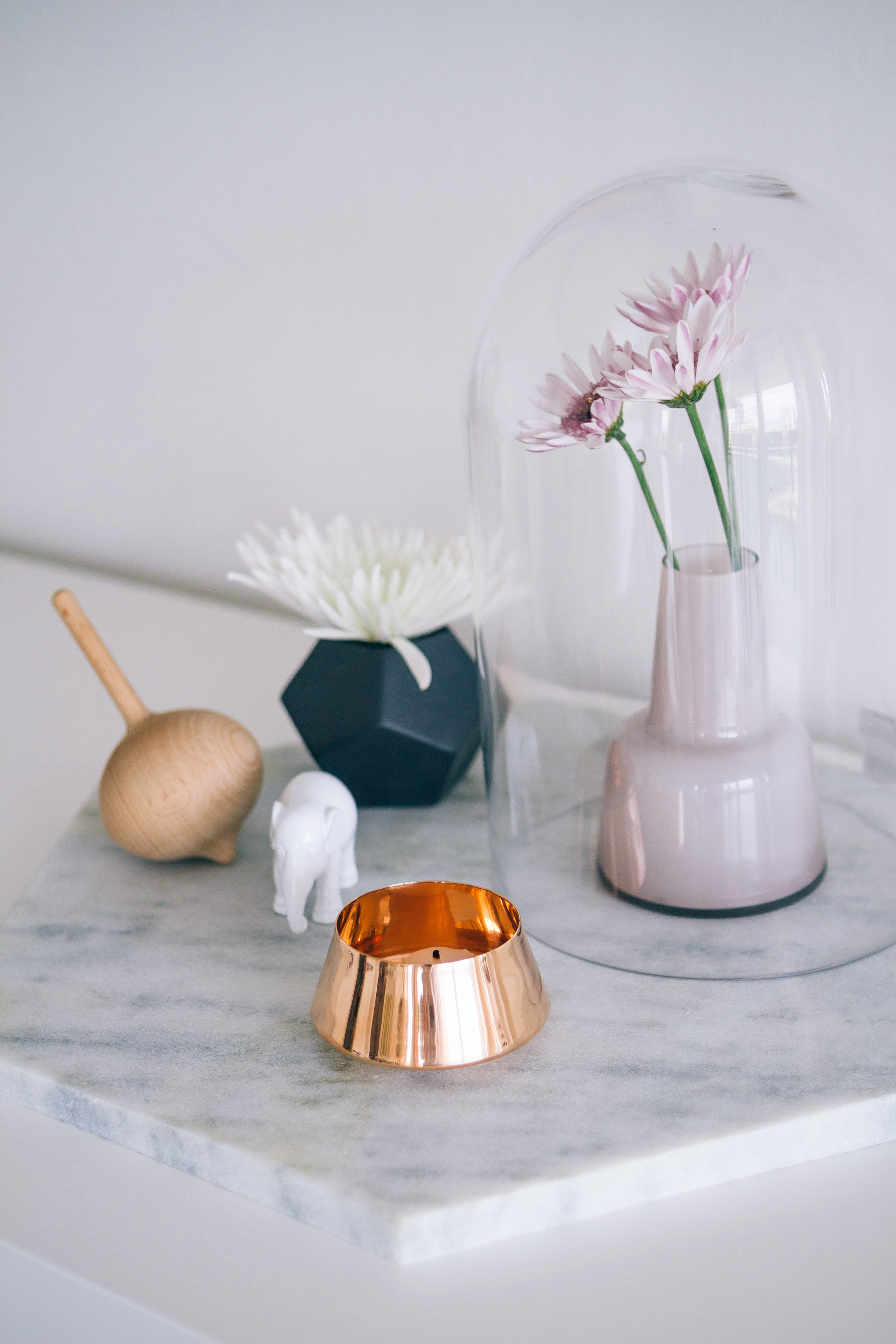 Marble tray, copper tea light holder, porcelain elephant, Hay spinning top, black geometric vase, glass dome with flowers 