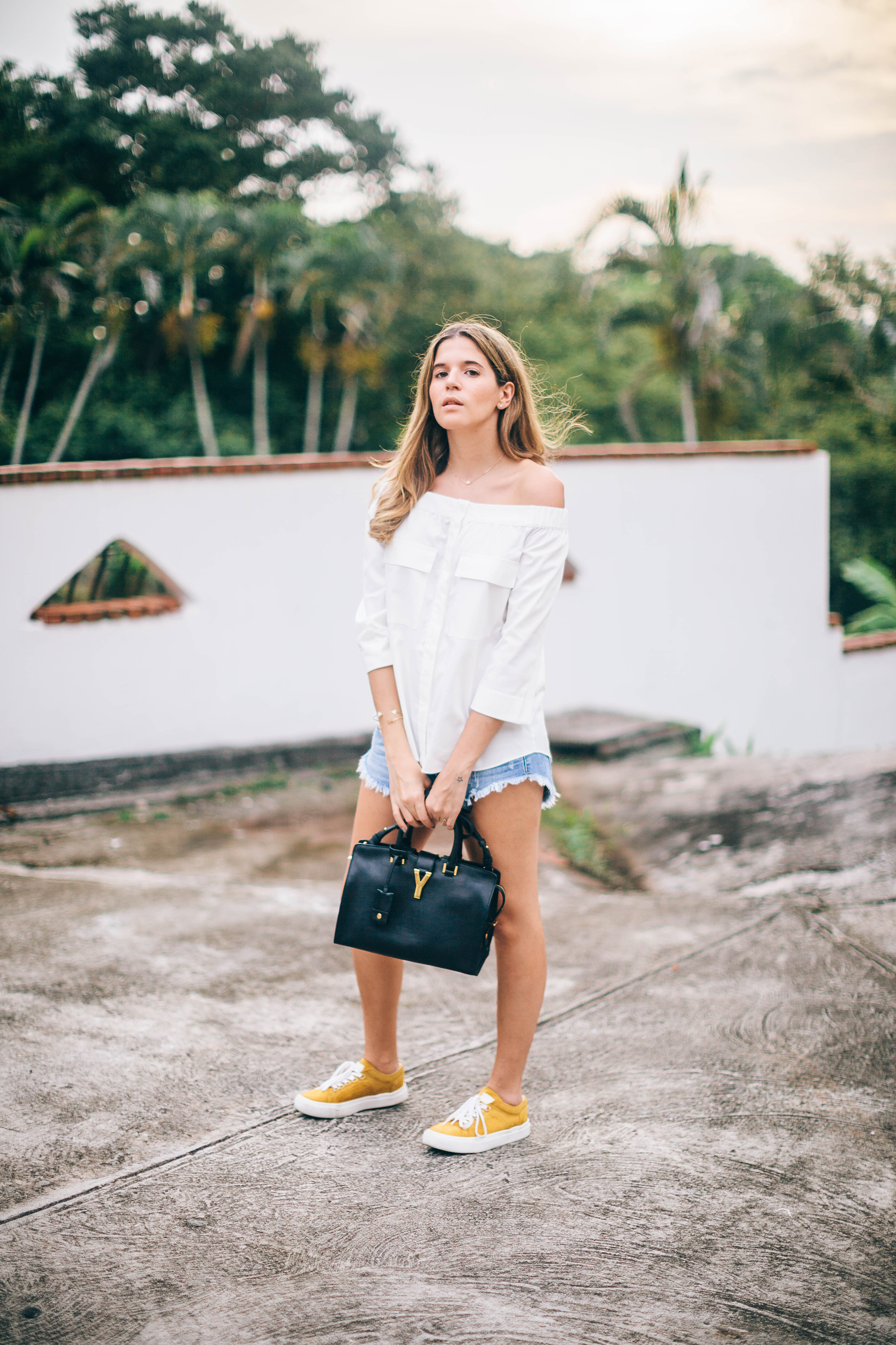 Blogger Maristella wearing an Off the Shoulder white top from H&M, Denim Cut off shorts and sneakers outfit