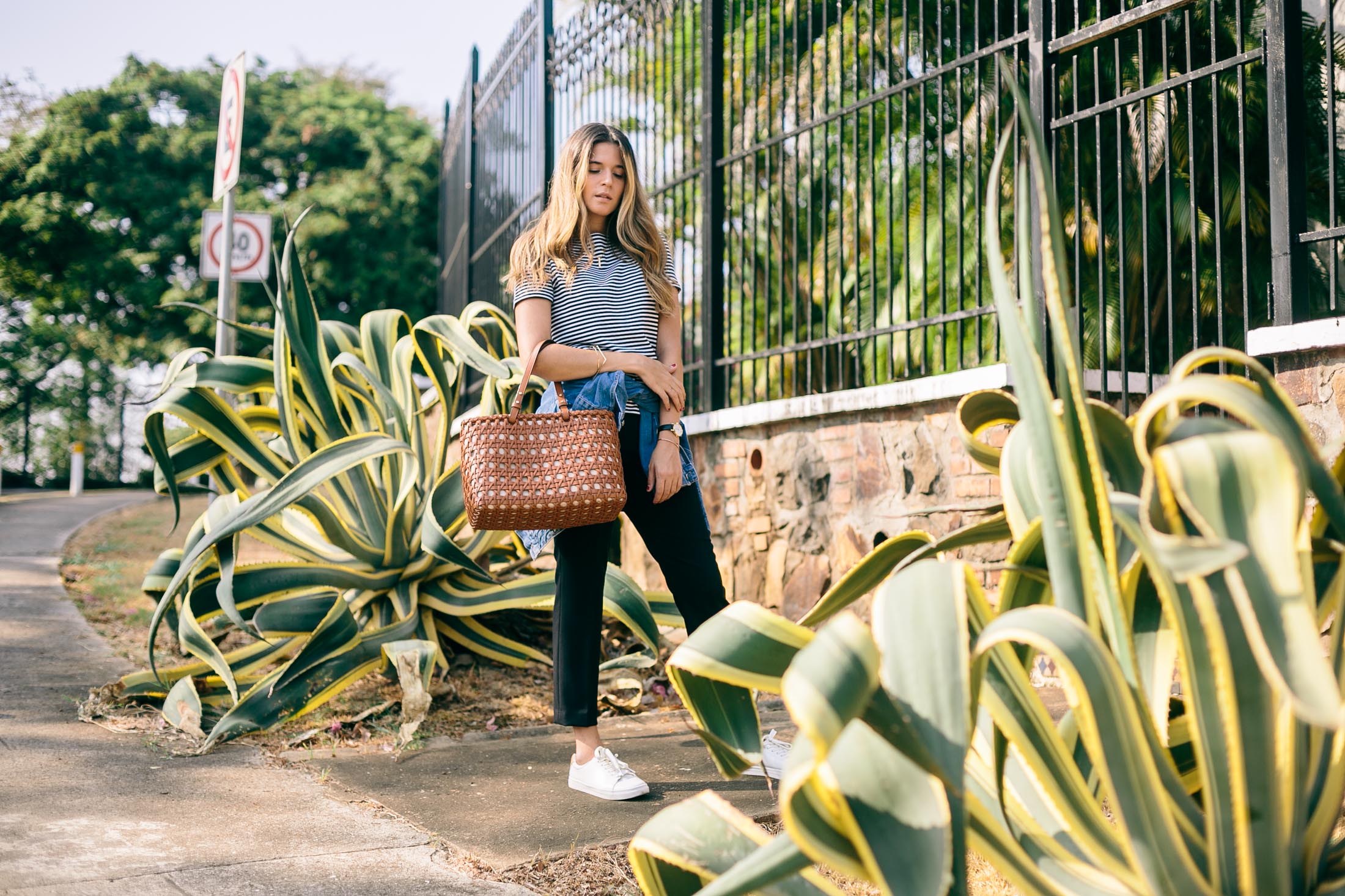 Blogger Maristella wears a tan leather basket weave tote bag by Kate Spade.