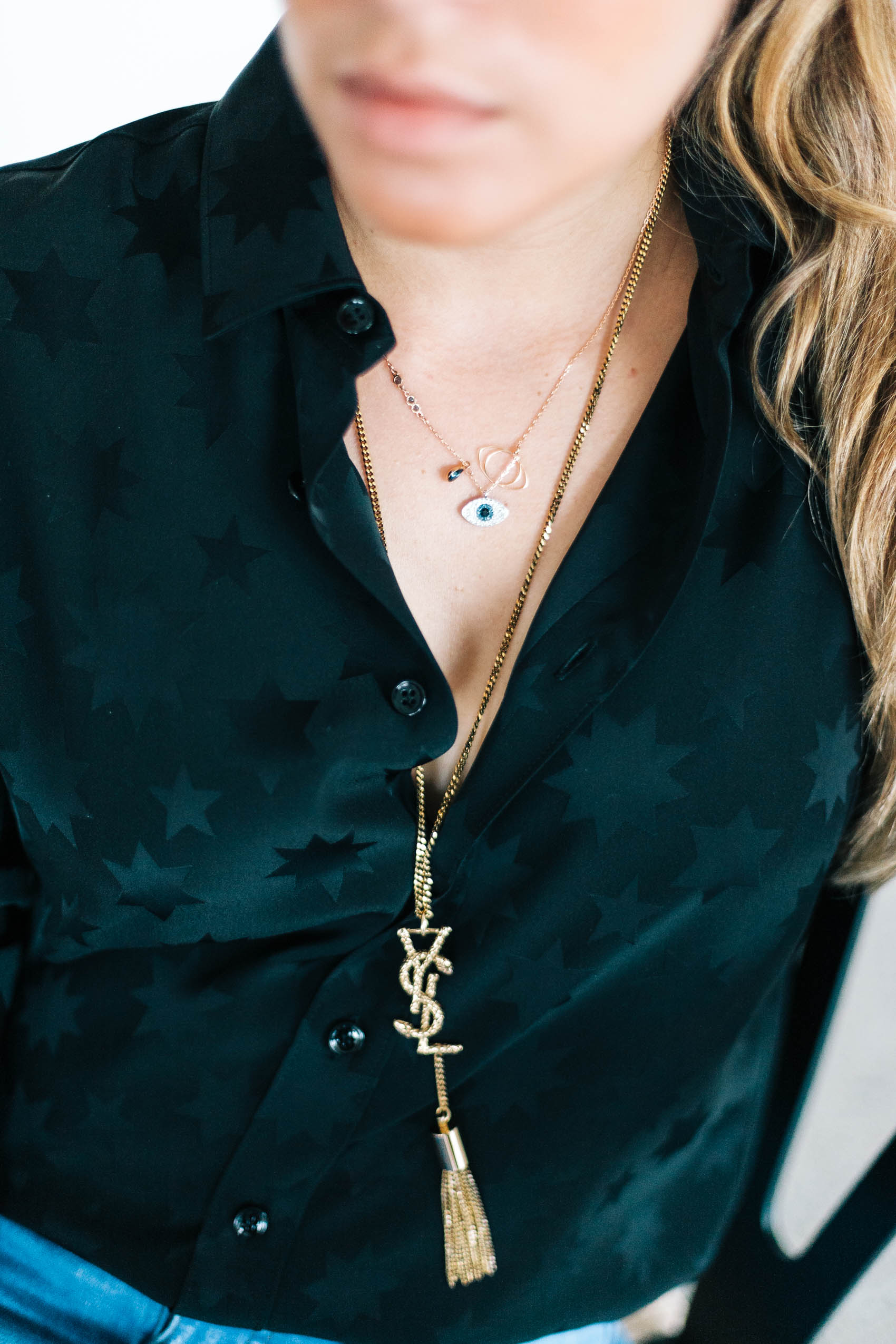 Swarovski by Miranda Kerr evil eye necklace layered with a long gold chain necklace from Saint Laurent with the Cassandre logo in snake and tassel