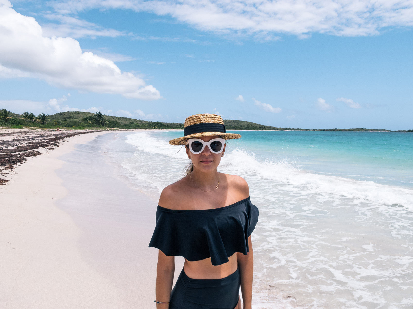 Vacation outfit idea, beach style OOTD by Maristella wearing a Zara straw hat, off shoulder black bikini top with high waisted bottoms and Celine oversize white sunglasses