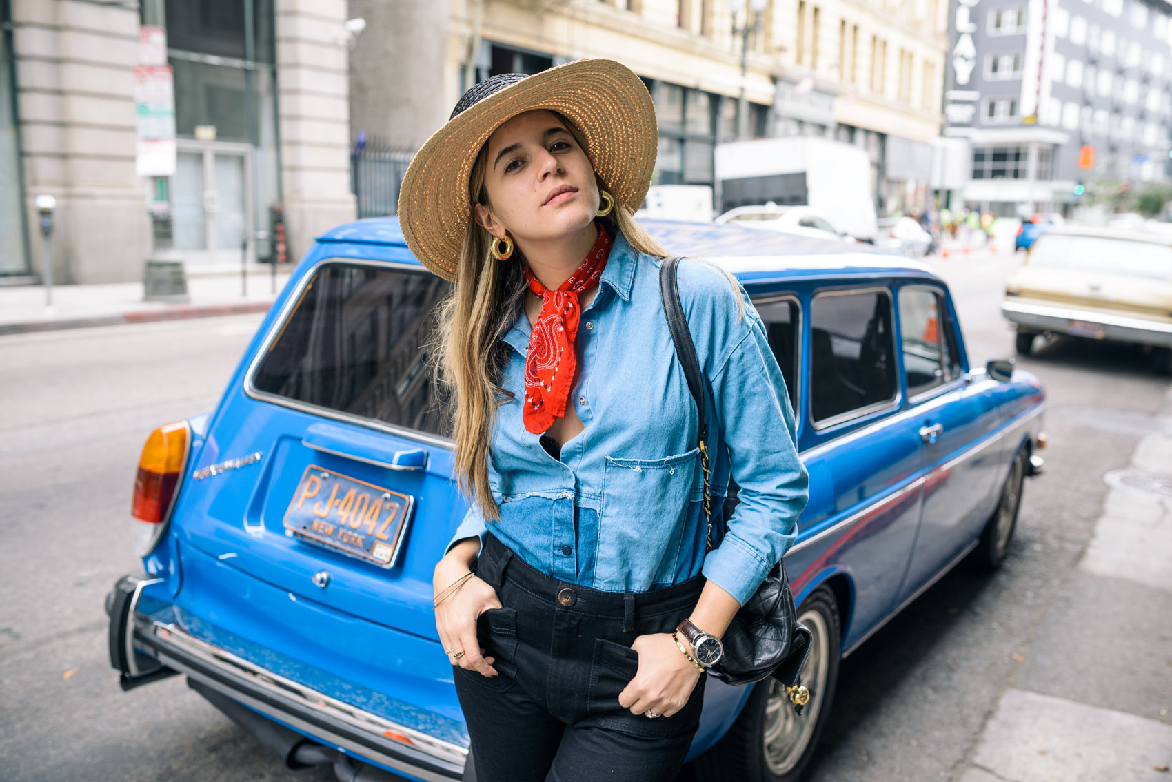 Latina blogger Maristella wearing a straw hat from Zara, red bandana neck scarf, patchwork denim shirt and black high waisted tassel jeans outfit