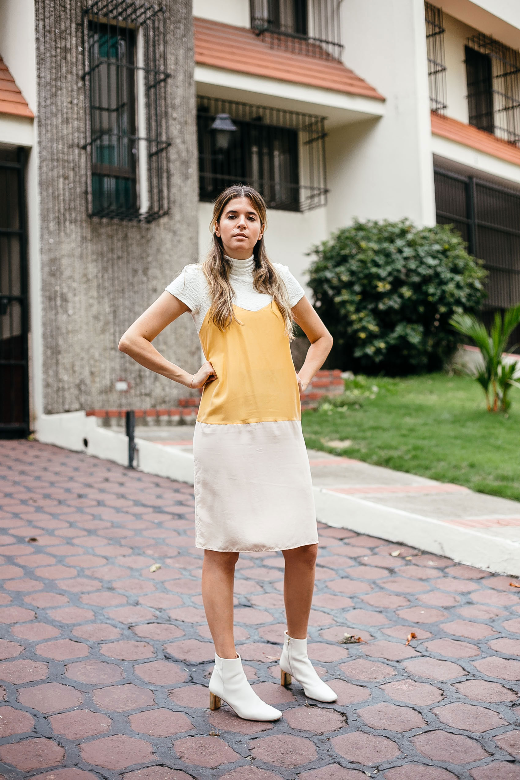 Blogger Maristella Gonzalez wearing an Alice + Olivia mock turtle neck cropped top with a color block silk slip dress from Tibi and white leather ankle boots from Uterqüe