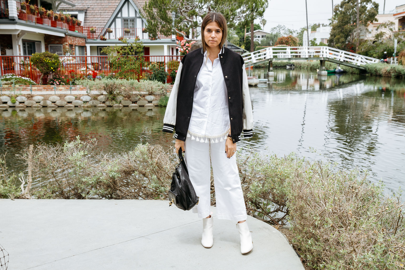 Blogger Maristella at the Venice Canals wearing a varsity jacket from Pull & Bear, shirt from Uterqüe, jeans from Zara, boots from Uterqüe, vintage Chanel bag