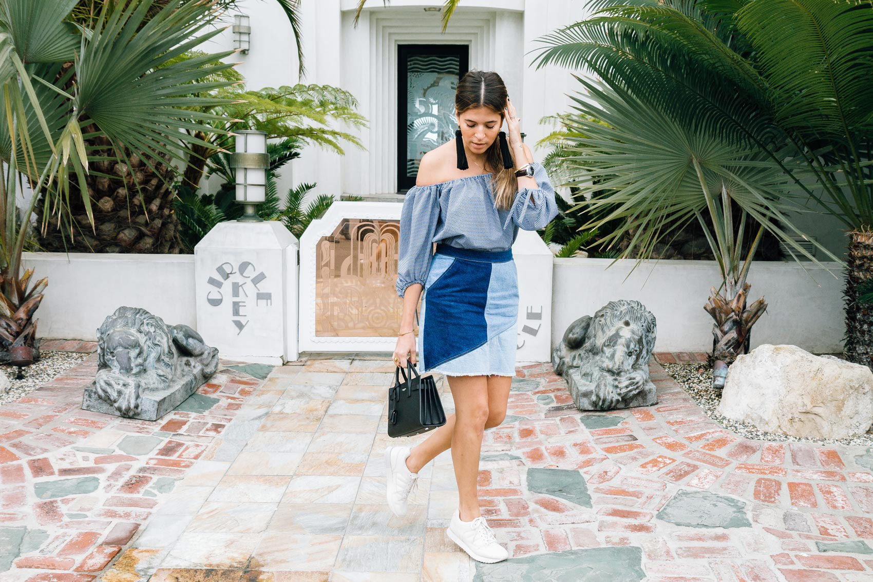 Blogger Maristella in Los Angeles wearing an off the shoulder top with A line denim skirt and sneakers