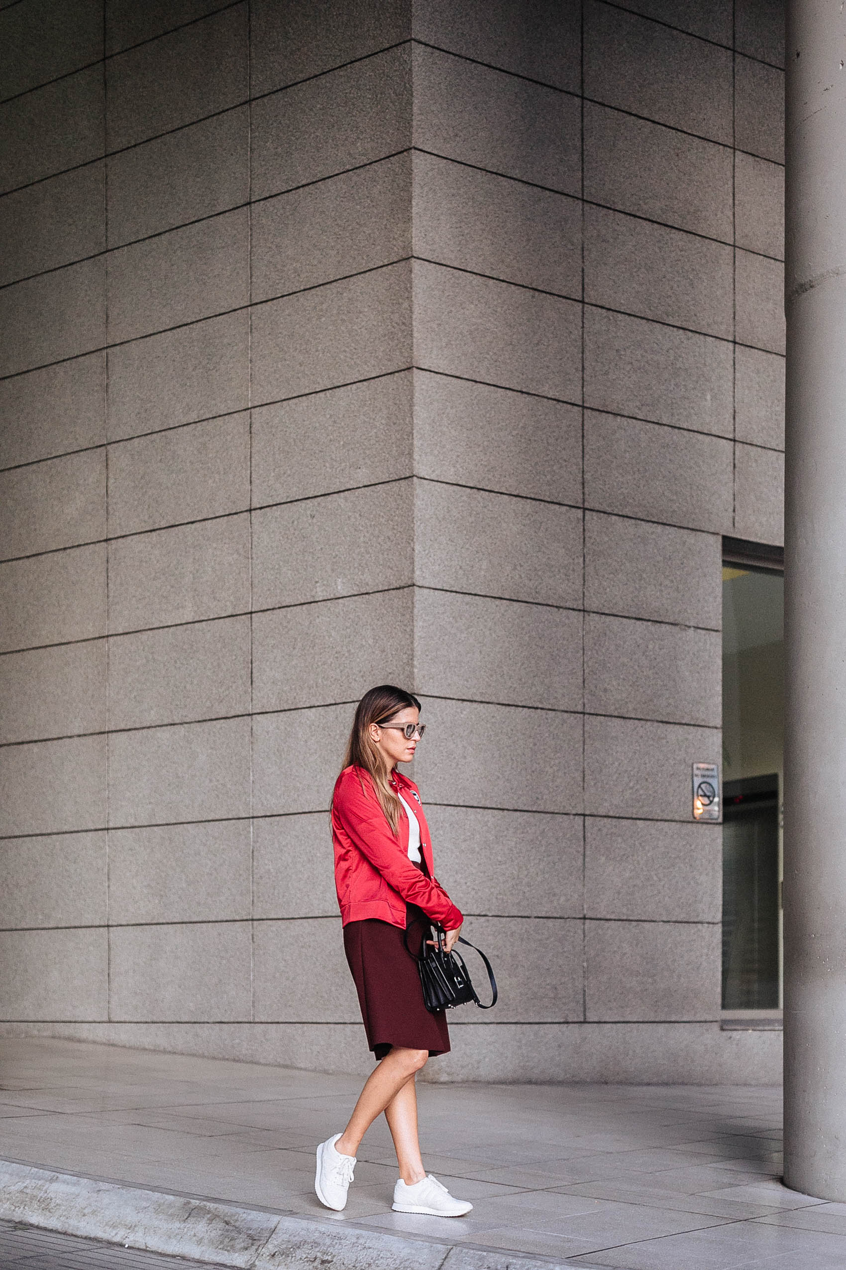 Blogger Maristella Gonzalez wearing a red bomber jacket, skirt and sneaker outfit