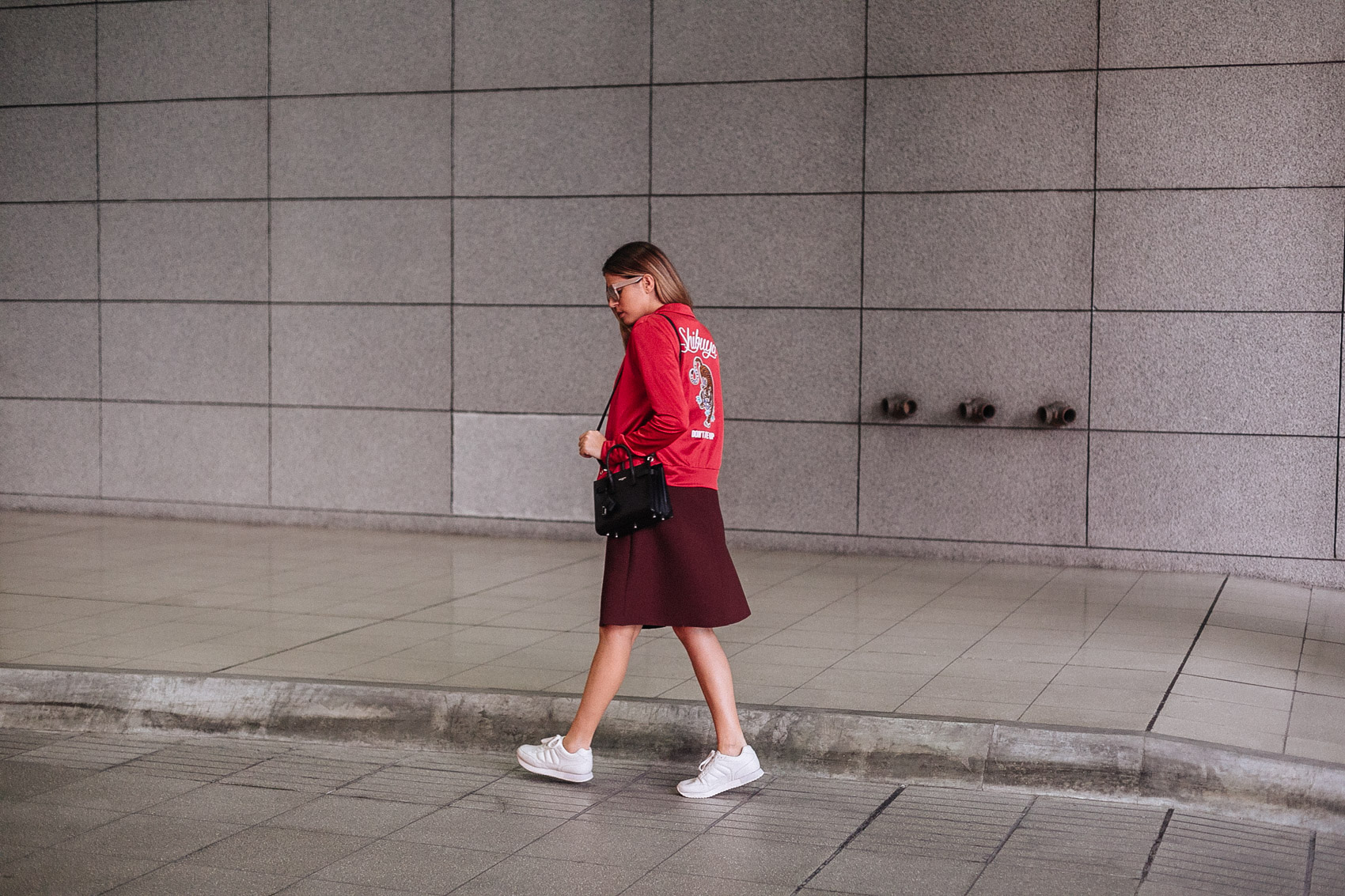 Blogger Maristella wearing a street style inspired outfit featuring different shades of red, a bomber jacker, sneakers and Saint Laurent Sac de Jour