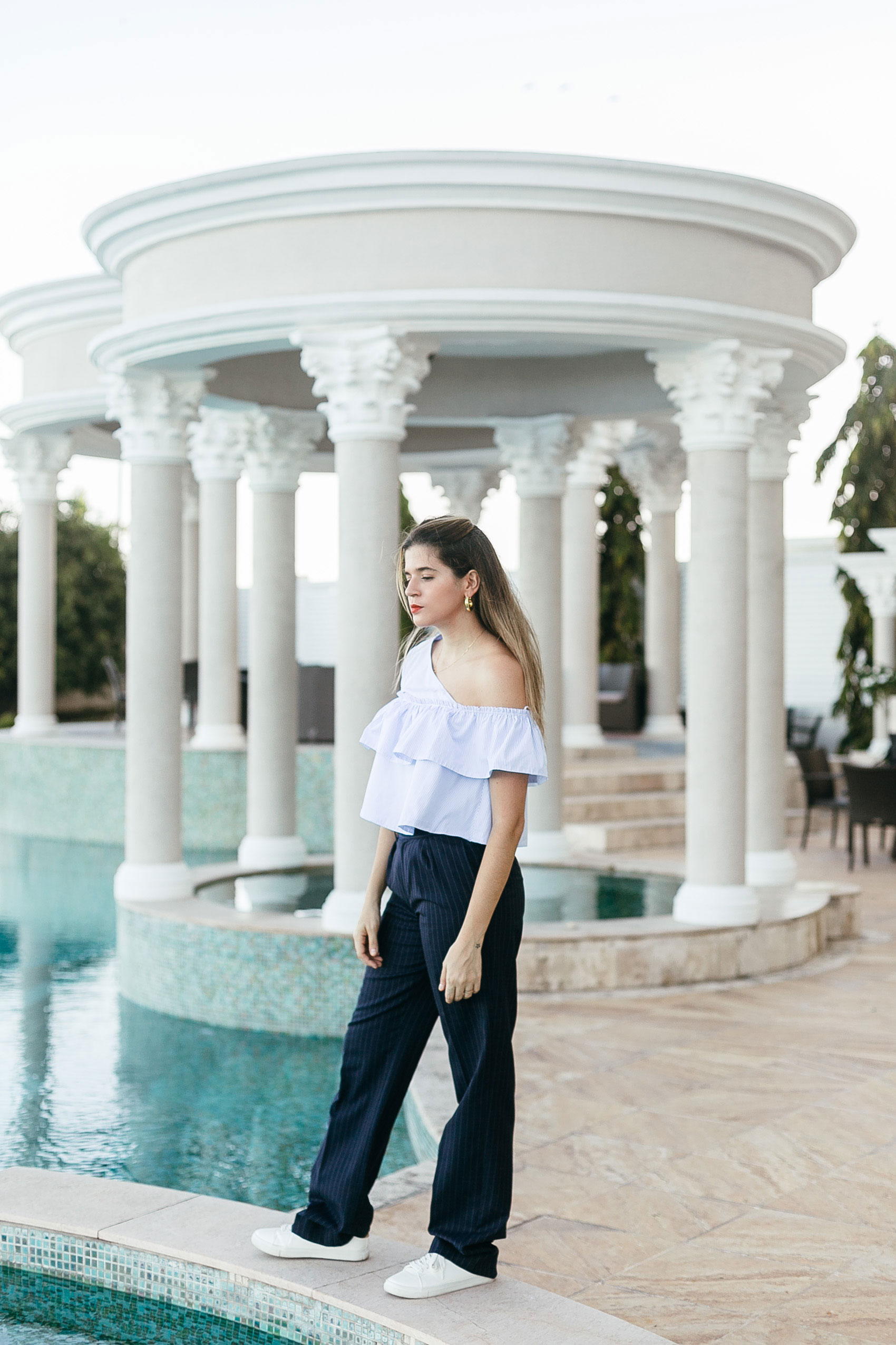 Blogger Maristella Gonzalez wearing a Zara one shoulder blue stripe stop with ruffle details, pinstripe trousers from Polo Ralph Lauren and H&M sneakers