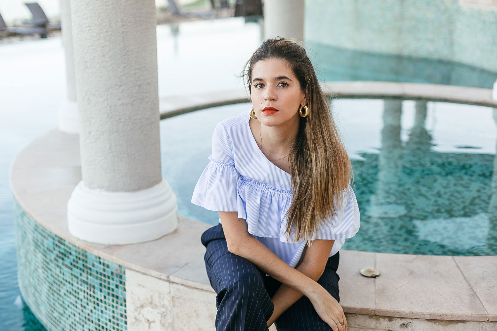 Maristella Gonzalez in a feminine ruffled one shoulder top from Zara, pinstripe pants from Polo Ralph Laurent, red lipstick and thick gold hoop earrings