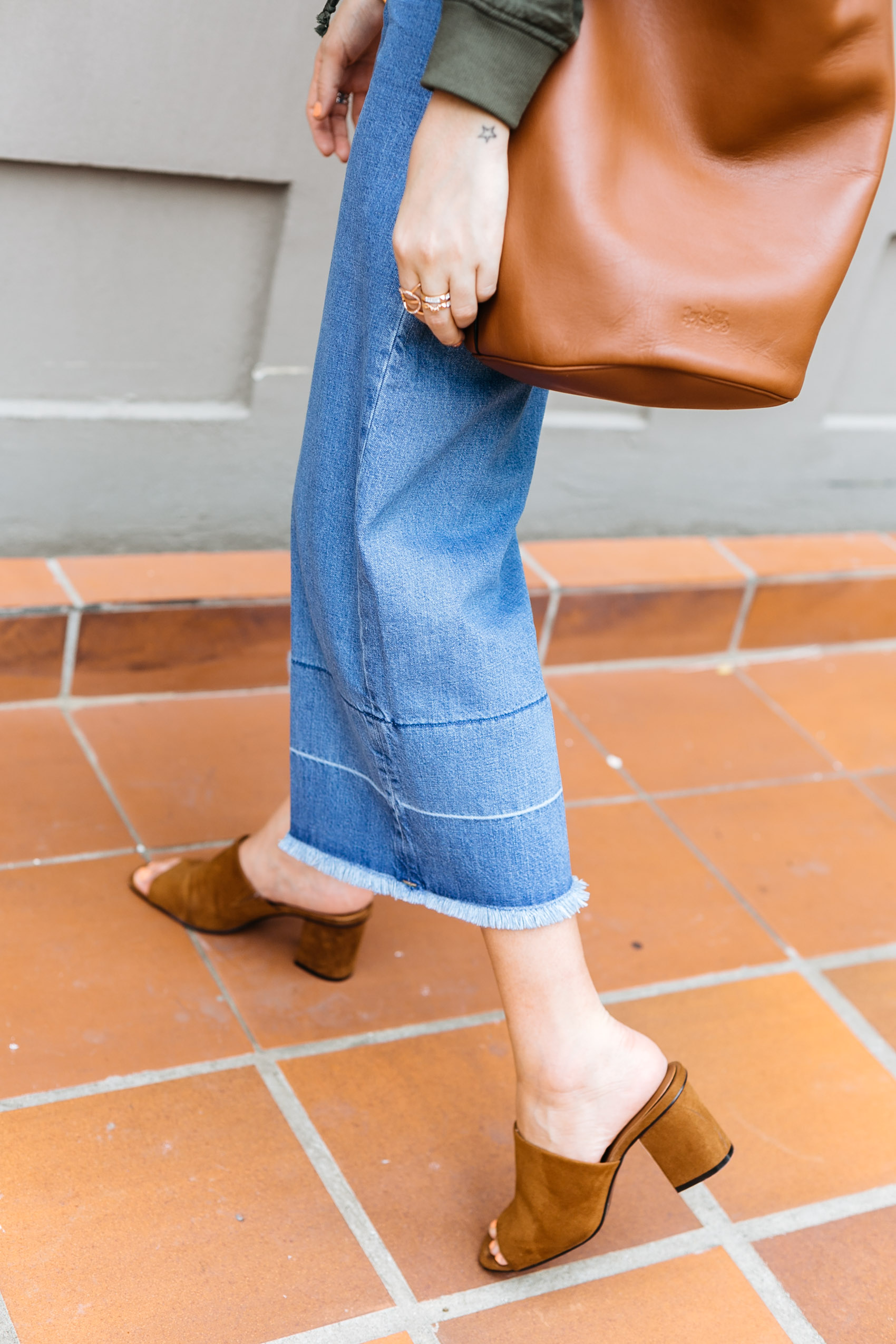 Maristella's outfit details: denim culottes with raw hem, suede mules from Zara in brown, tan leather Coach bucket bag