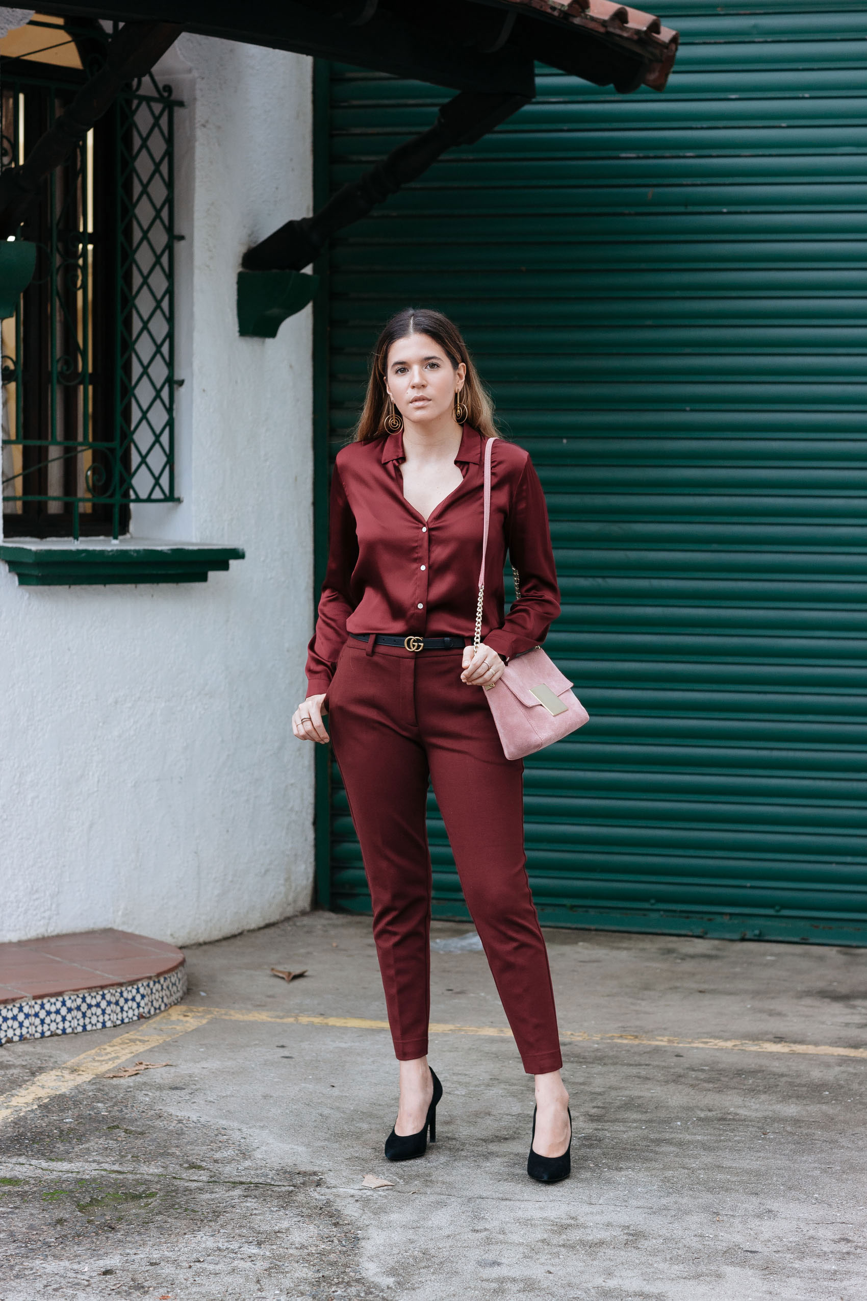 Blogger Maristella Gonzalez wearing a burgundy silk pijama style blouse with burgundy tapered trousers, black suede pumps from Zara and dusty rose pink suede bag from Purificacion Garcia, skinny Gucci monogram belt