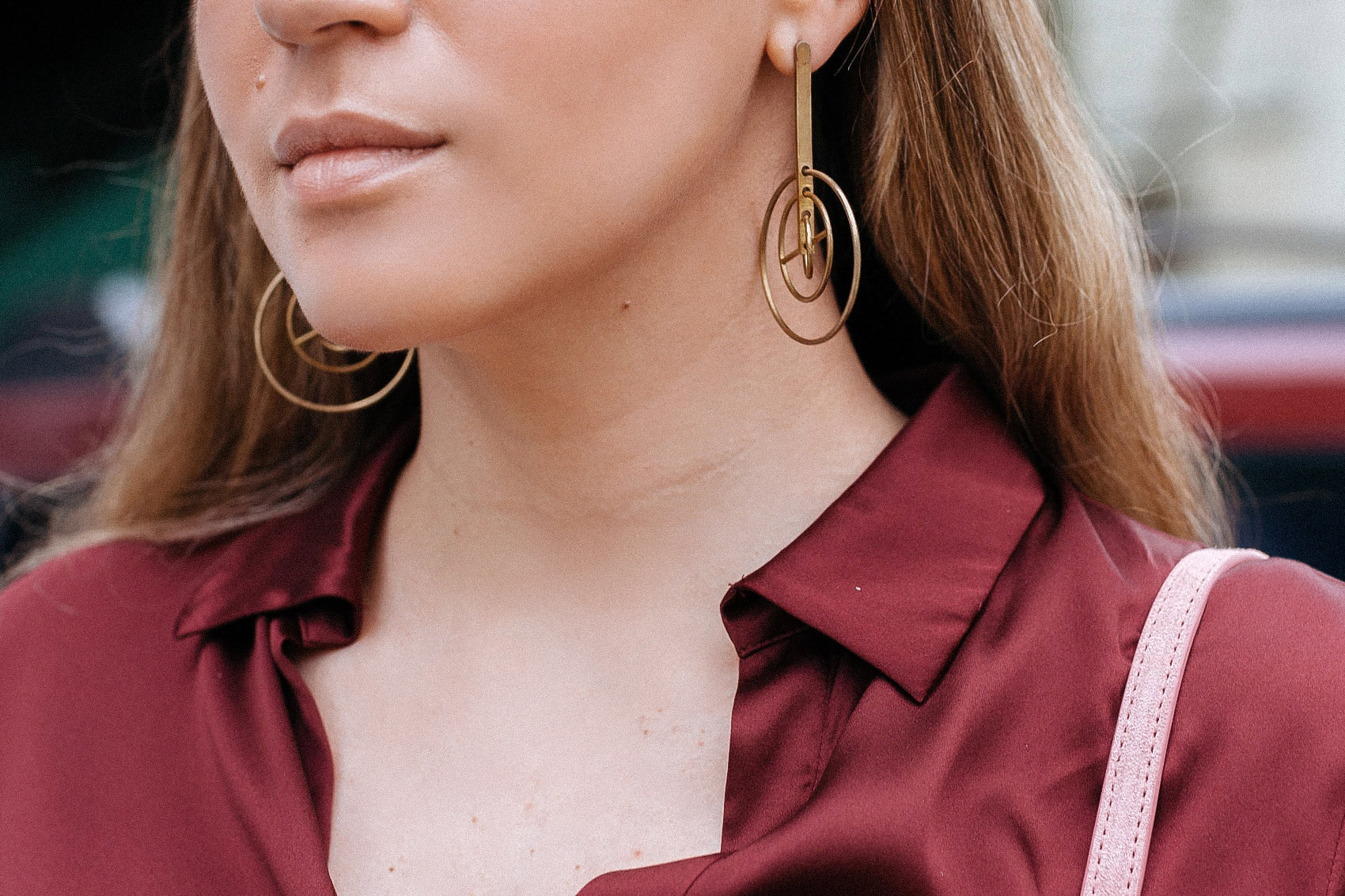 Maristella wears a pijama style silk blouse in burgundy with mobile Metalepsis Projects earrings