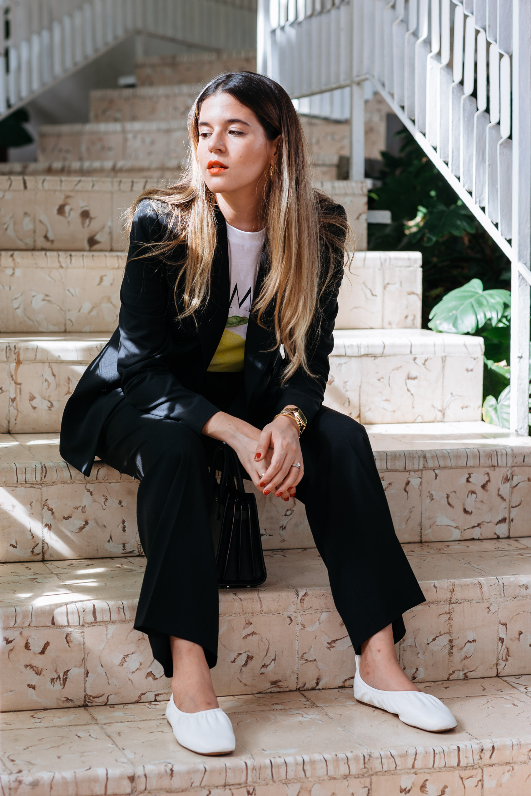 Maristella in a chic and comfortable work outfit idea with a black suit, graphic tee and flat shoes