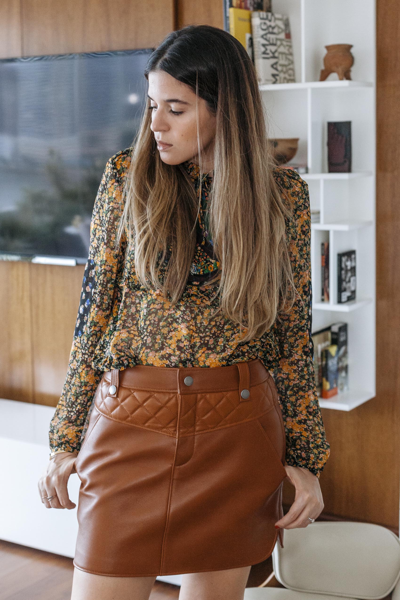 Maristella wears Coach 1941 floral blouse and tan leather skirt