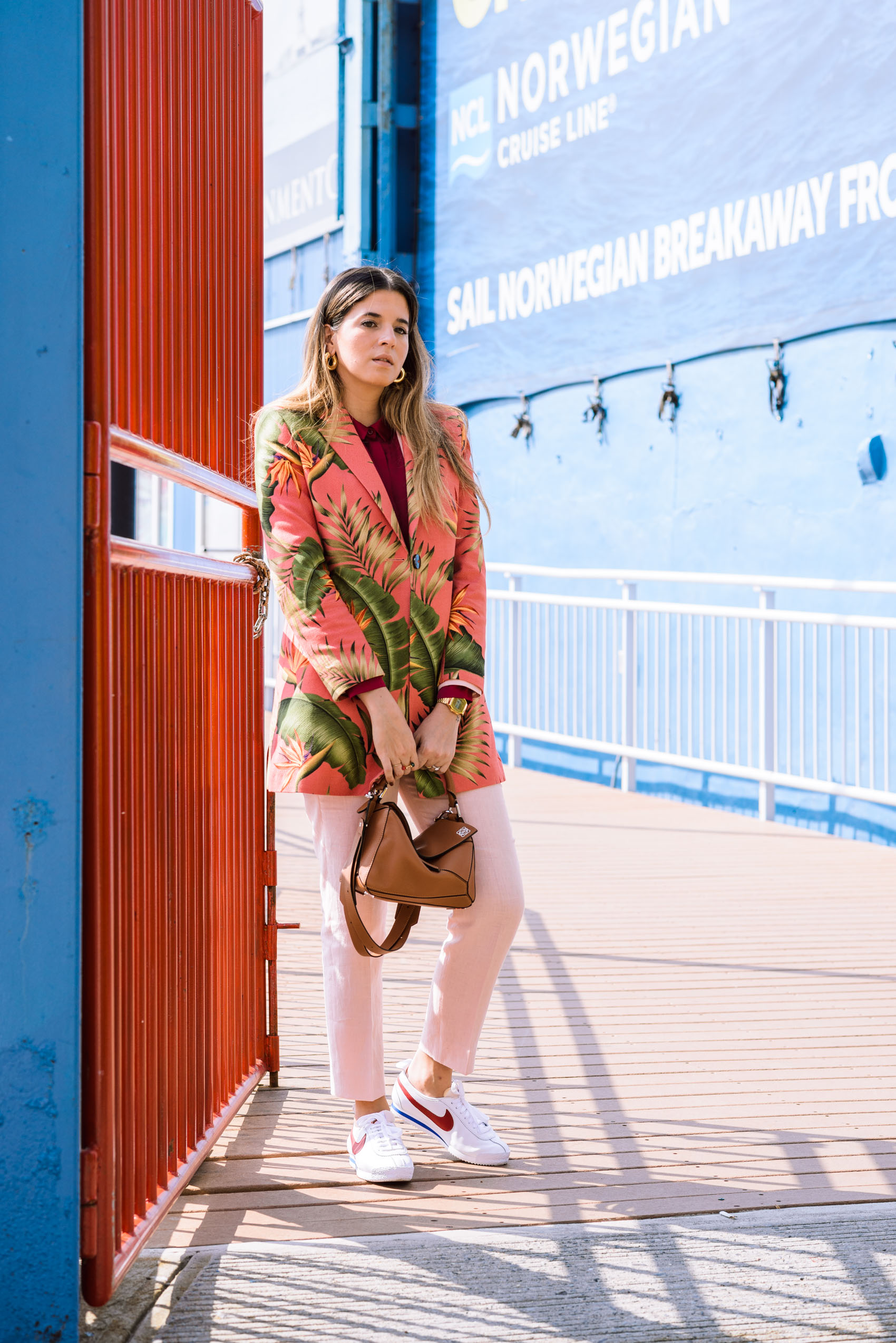 Blogger Maristella from Panama wears a pink tropical print suit with Nike sneakers and Loewe bag
