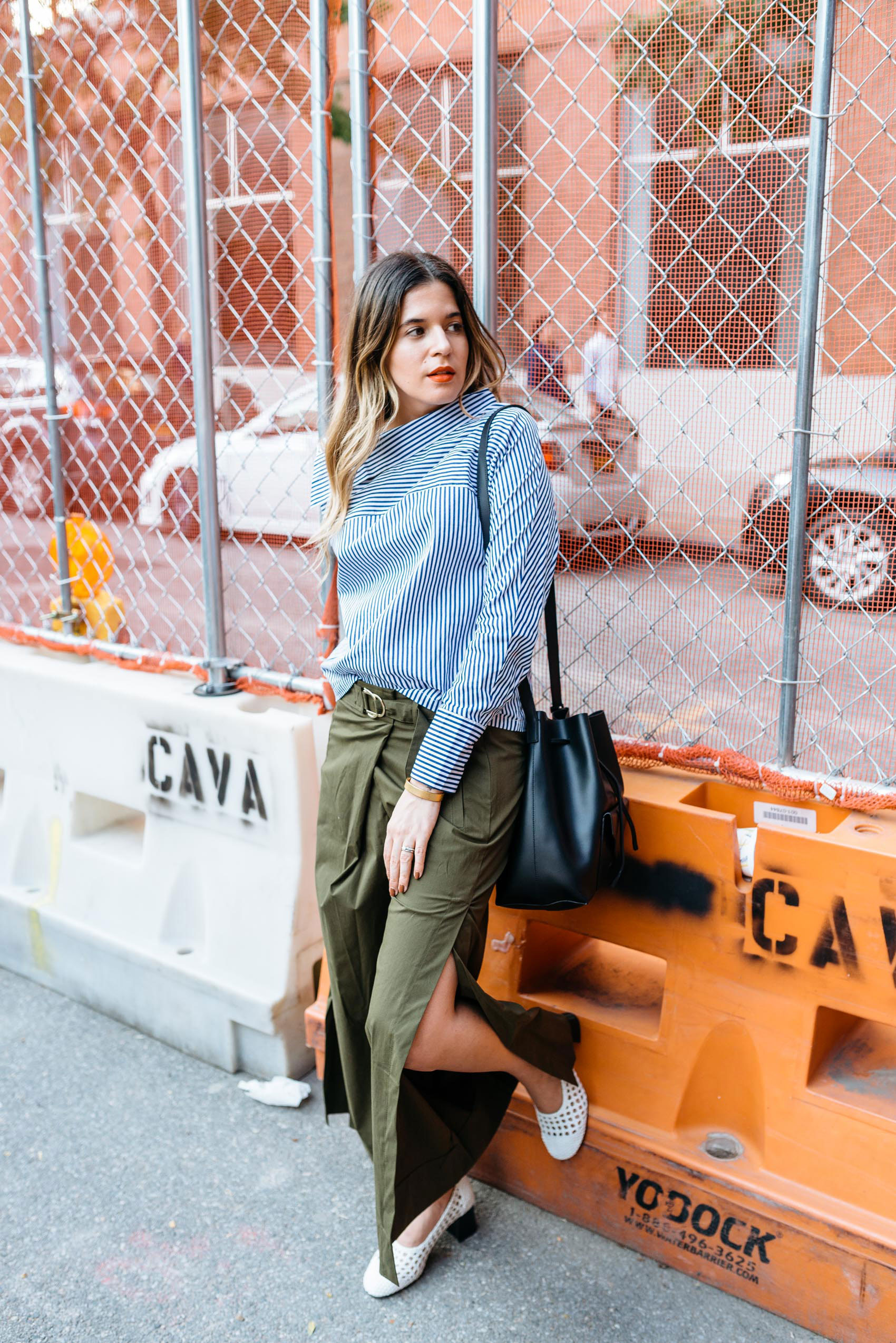 Maristella in New York wearing a blue stripe blouse with button down sleeves, Zara wide leg olive trousers, Sandro shoes and black leather drawstring bucket bag