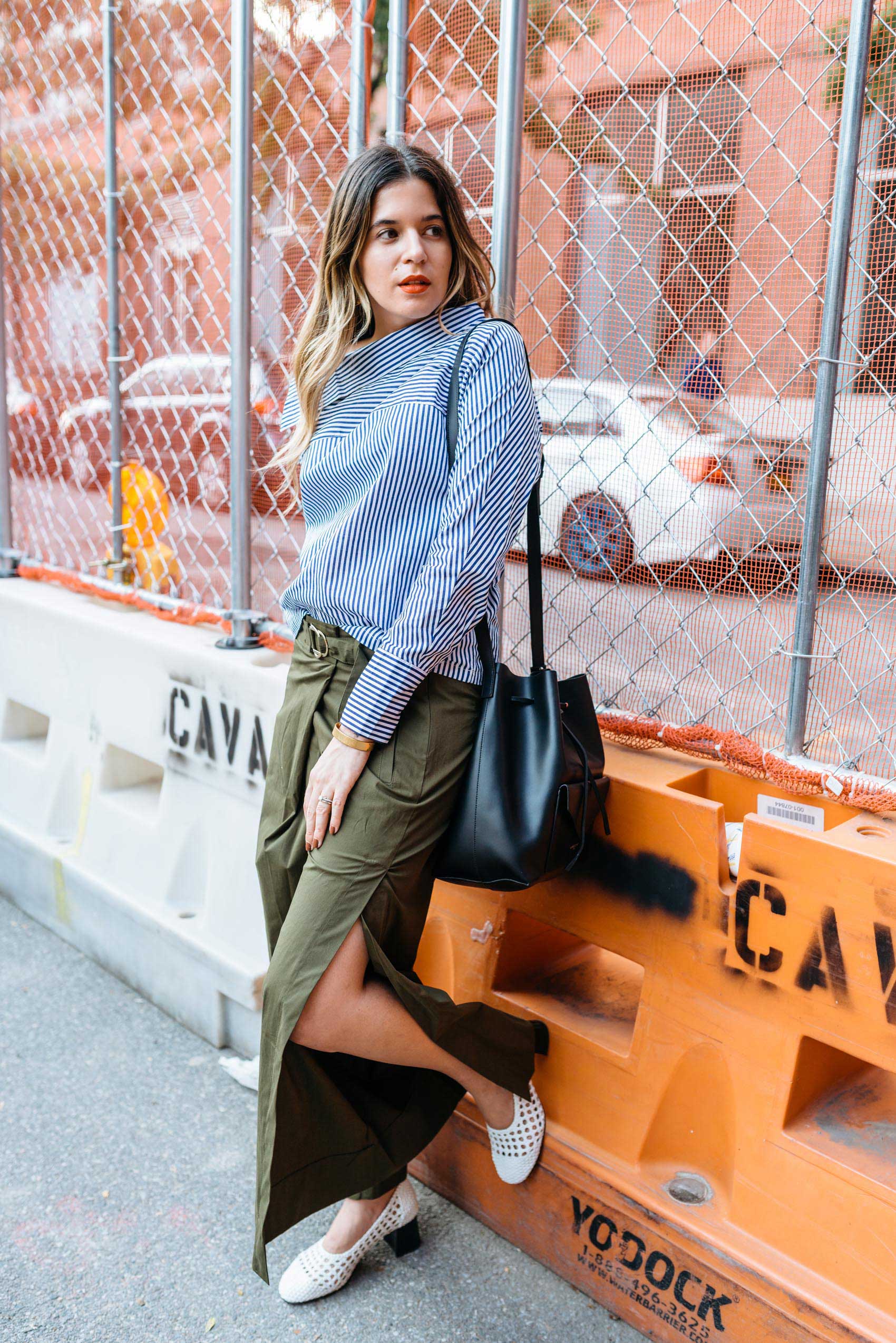 Blogger Maristella wears open leg pants with a blue stripe shirt, white braided leather shoes and black bucket bag