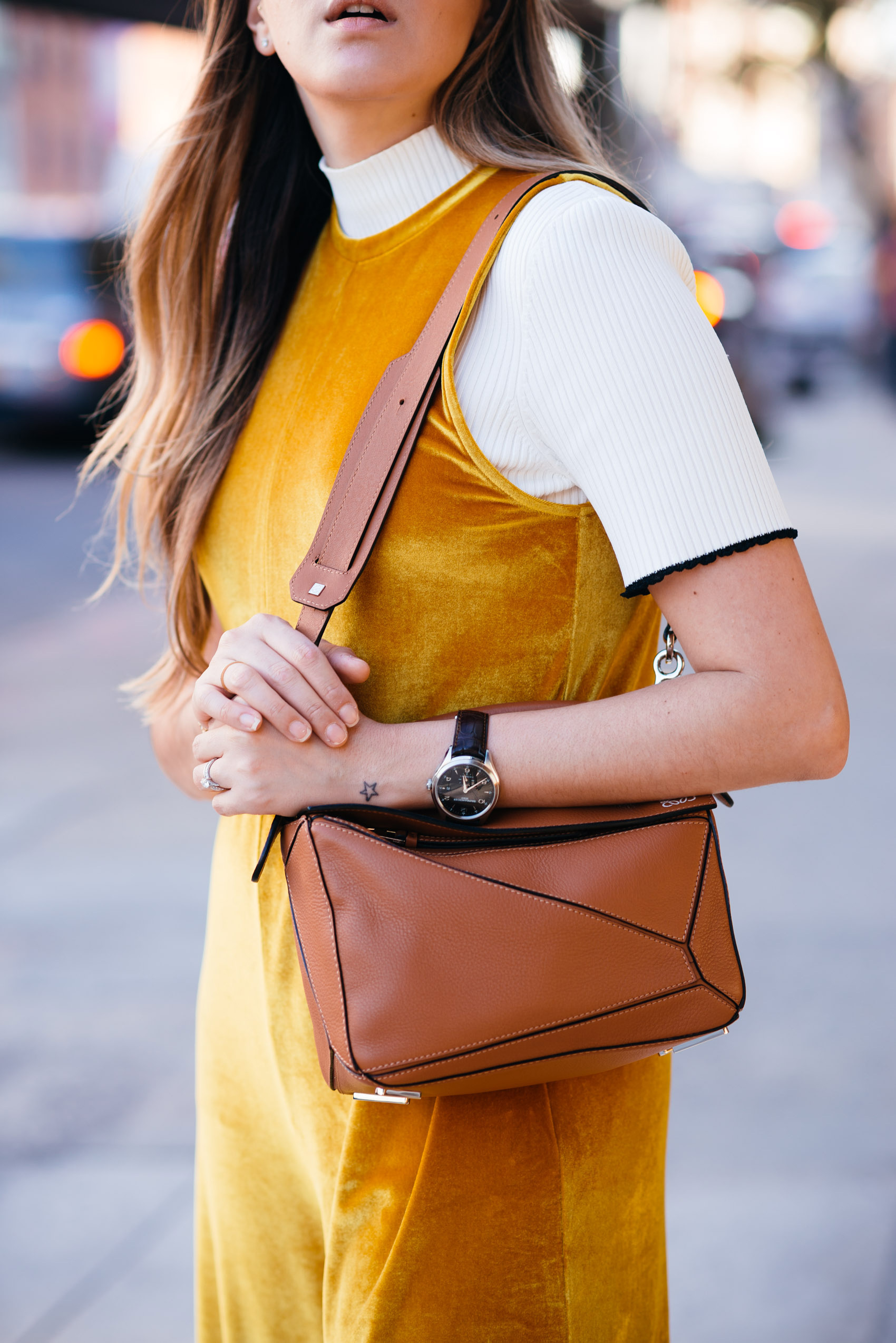 Maristella wearing a yellow gold jumpsuit with a ribbed contrast sleeve sweater and Loewe bag by Jonathan Anderson