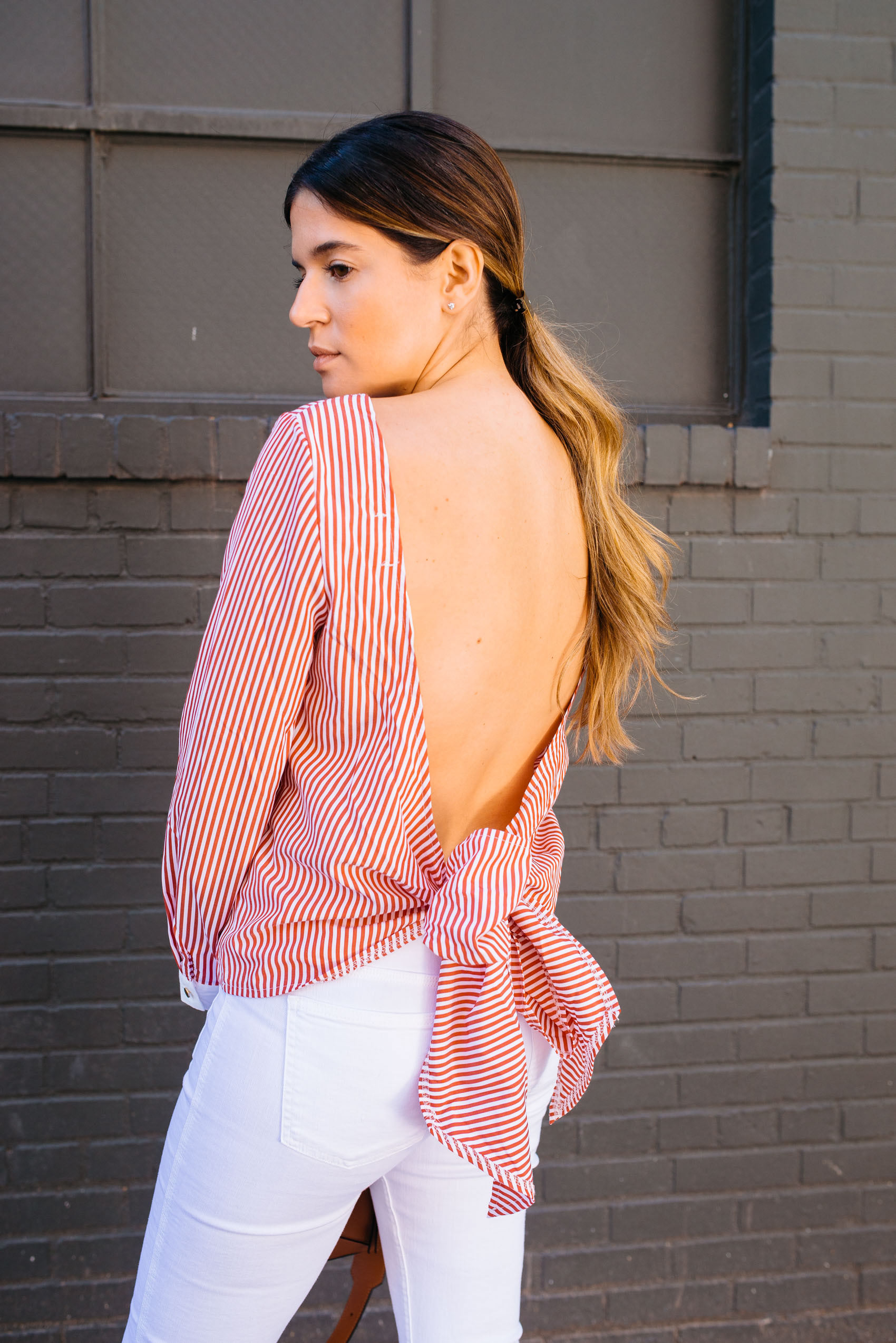 Maristella in an elegant and sexy open back blouse with white denim