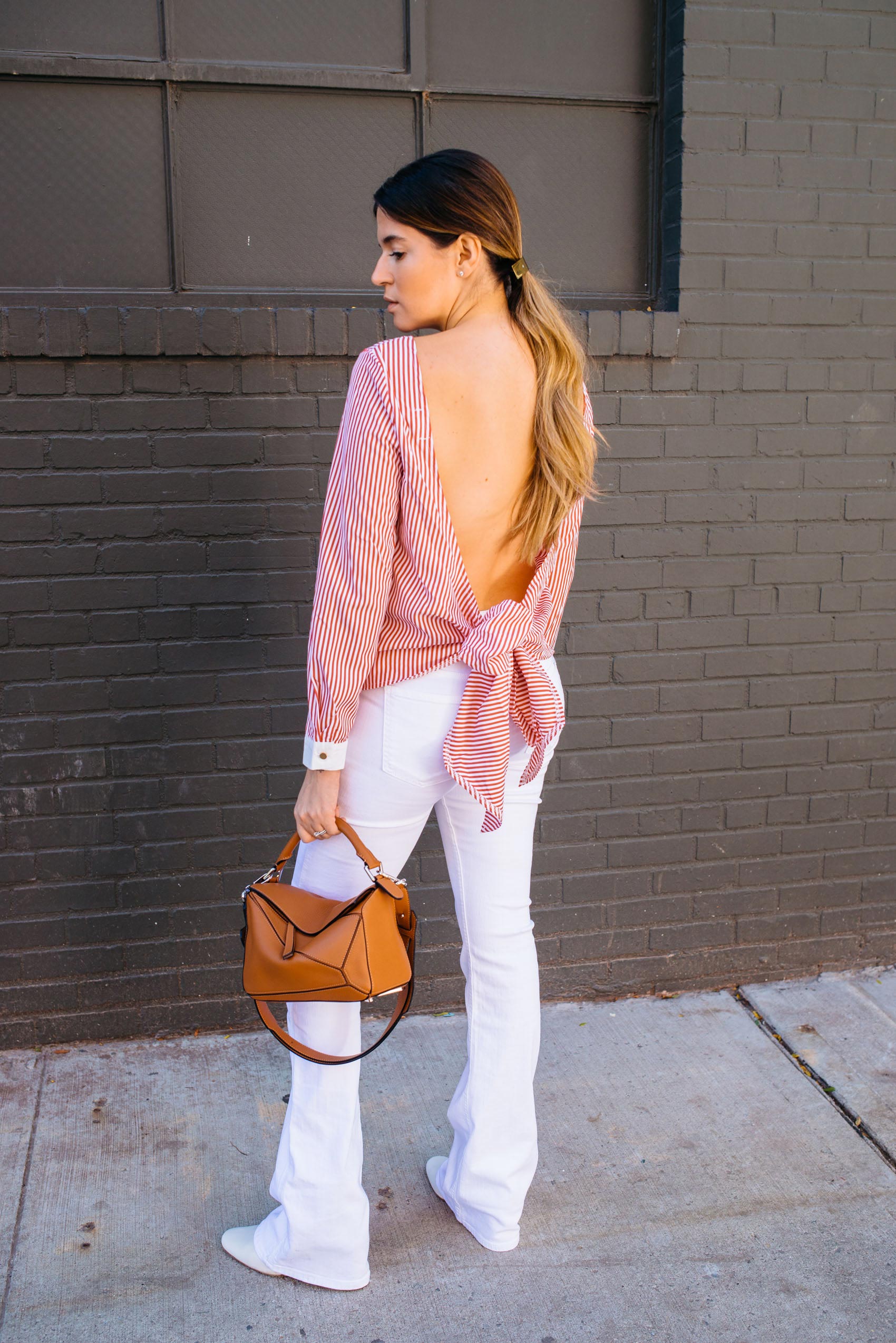 Maristella of A Constellation in a minimal chic and easy Fall outfit idea with an open back blouse and flared white jeans
