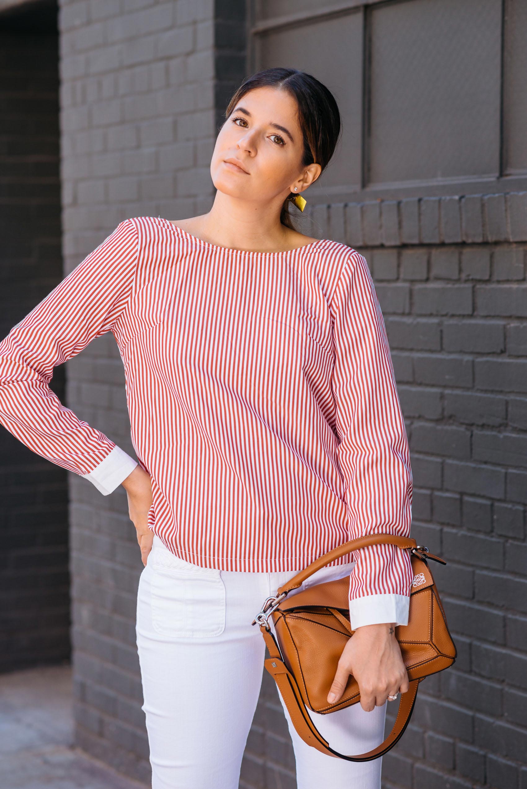 Maristella in a red stripe blouse with white cuff details, denim and Loewe Puzzle bag