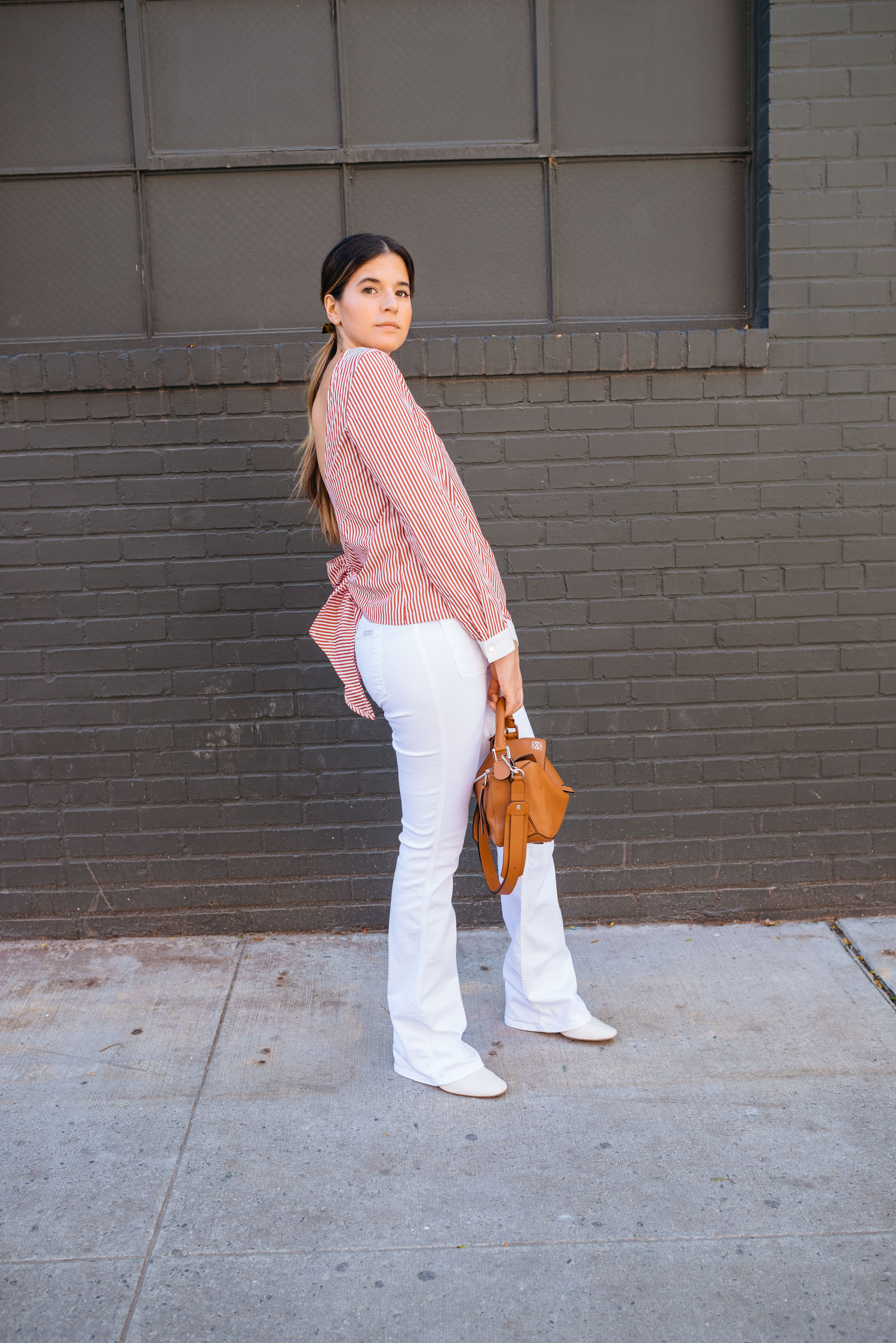 Blogger Maristella in NYFW wearing white flared jeans, ankle boots and a striped blouse