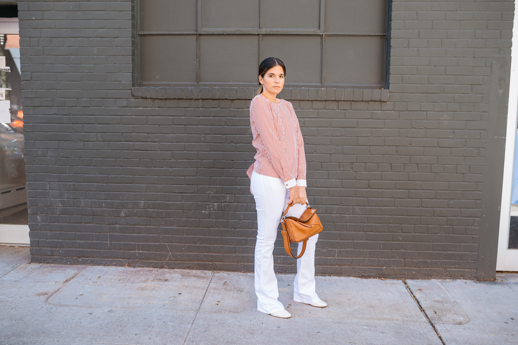 Maristella in a chic open back version of a banker's shirt, flared jeans and Loewe bag