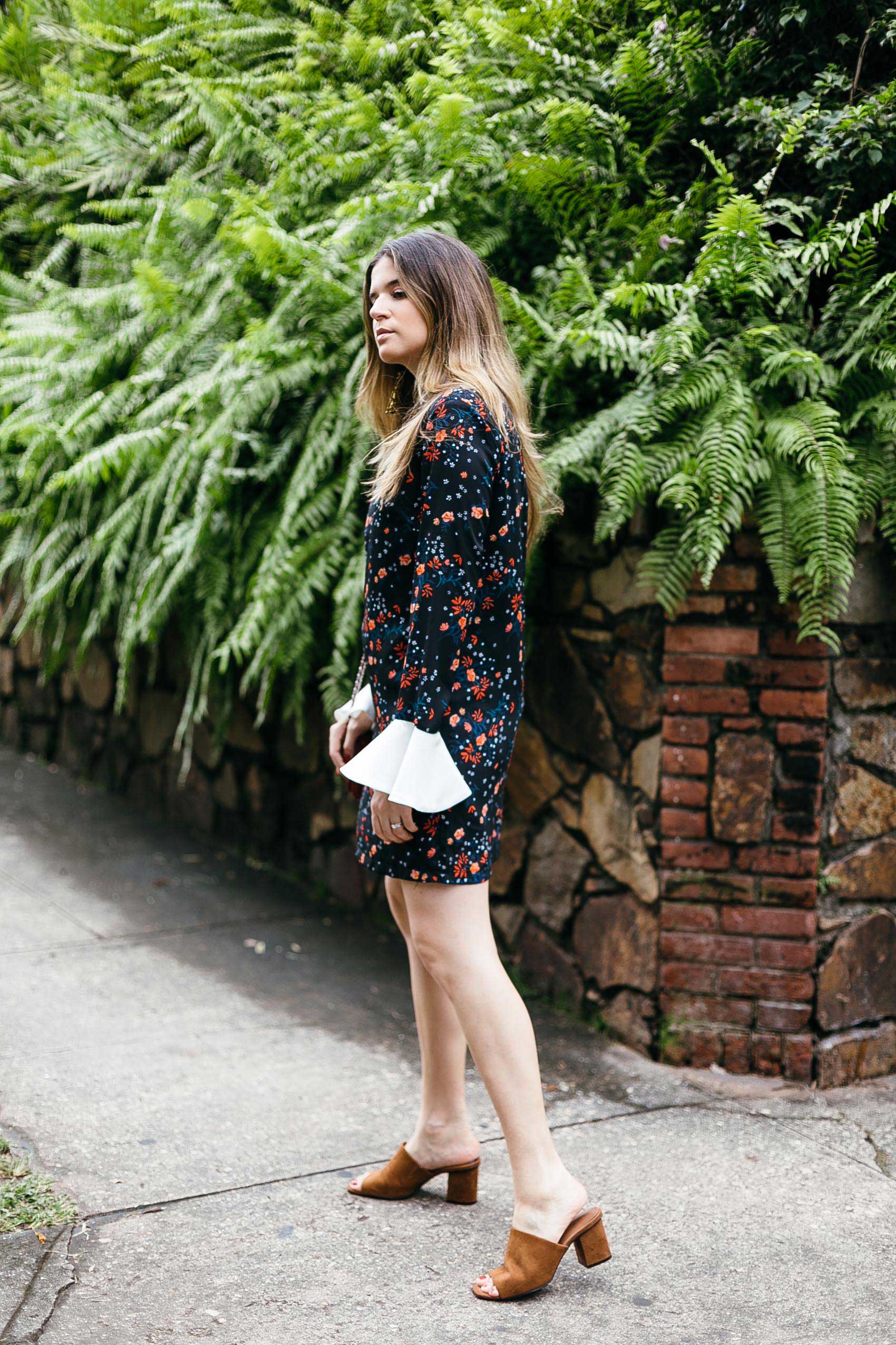 Maristella wearing a black floral dress and suede block heel mules