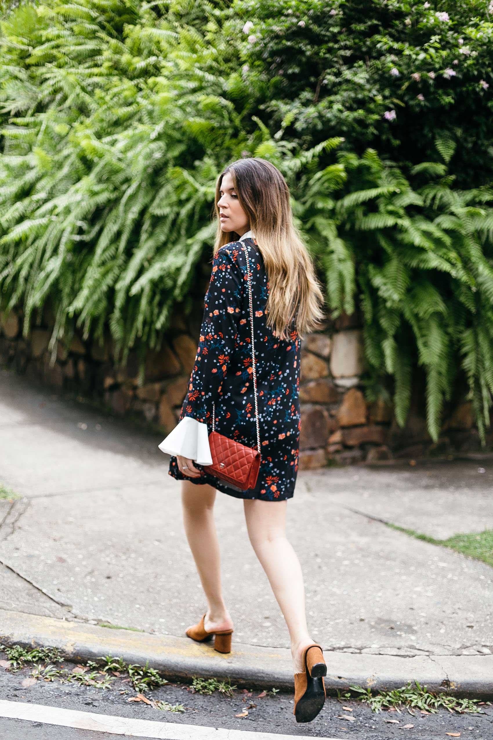 Maristella wears a floral cocktail dress with Chanel red chain wallet