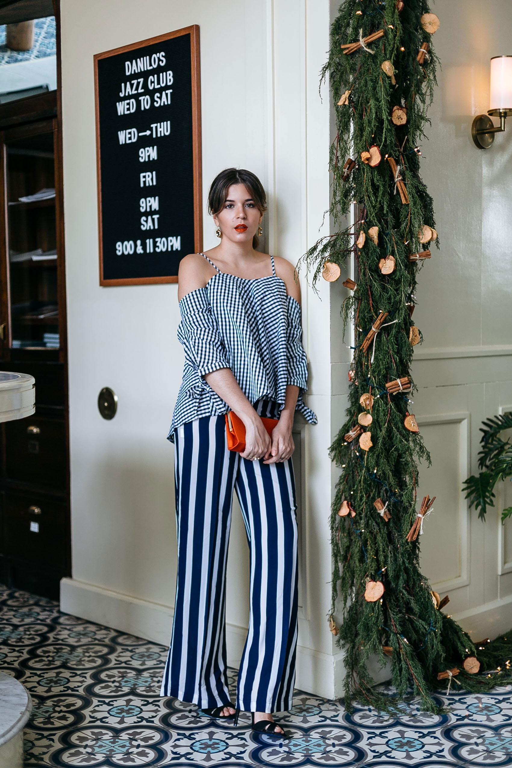 Maristella wears a gingham blouse with stripe wide leg pants and black strappy Schutz sandals