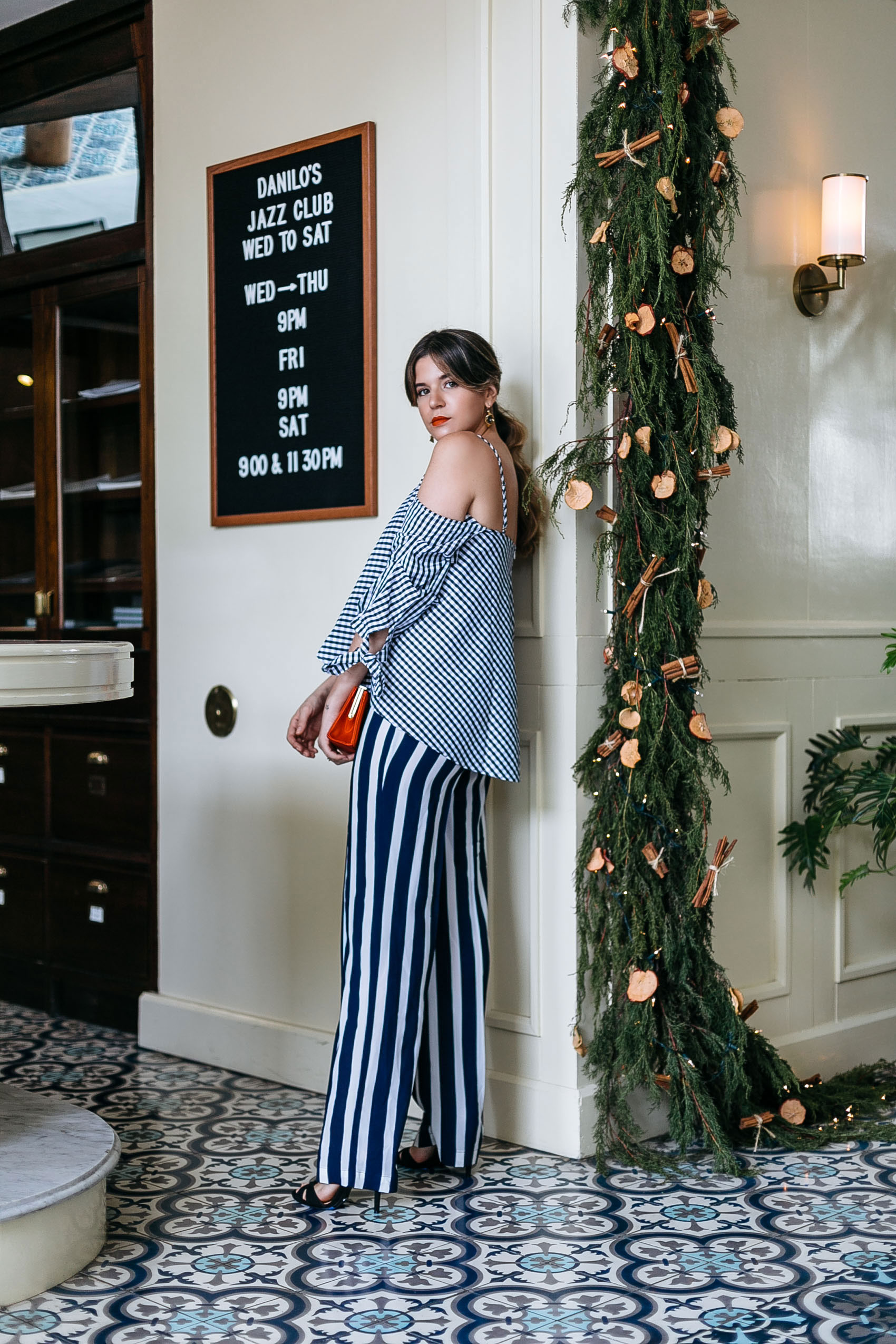 Maristella's Holiday season party outfit idea with a gingham off shoulder shirt and stripe wide leg pants