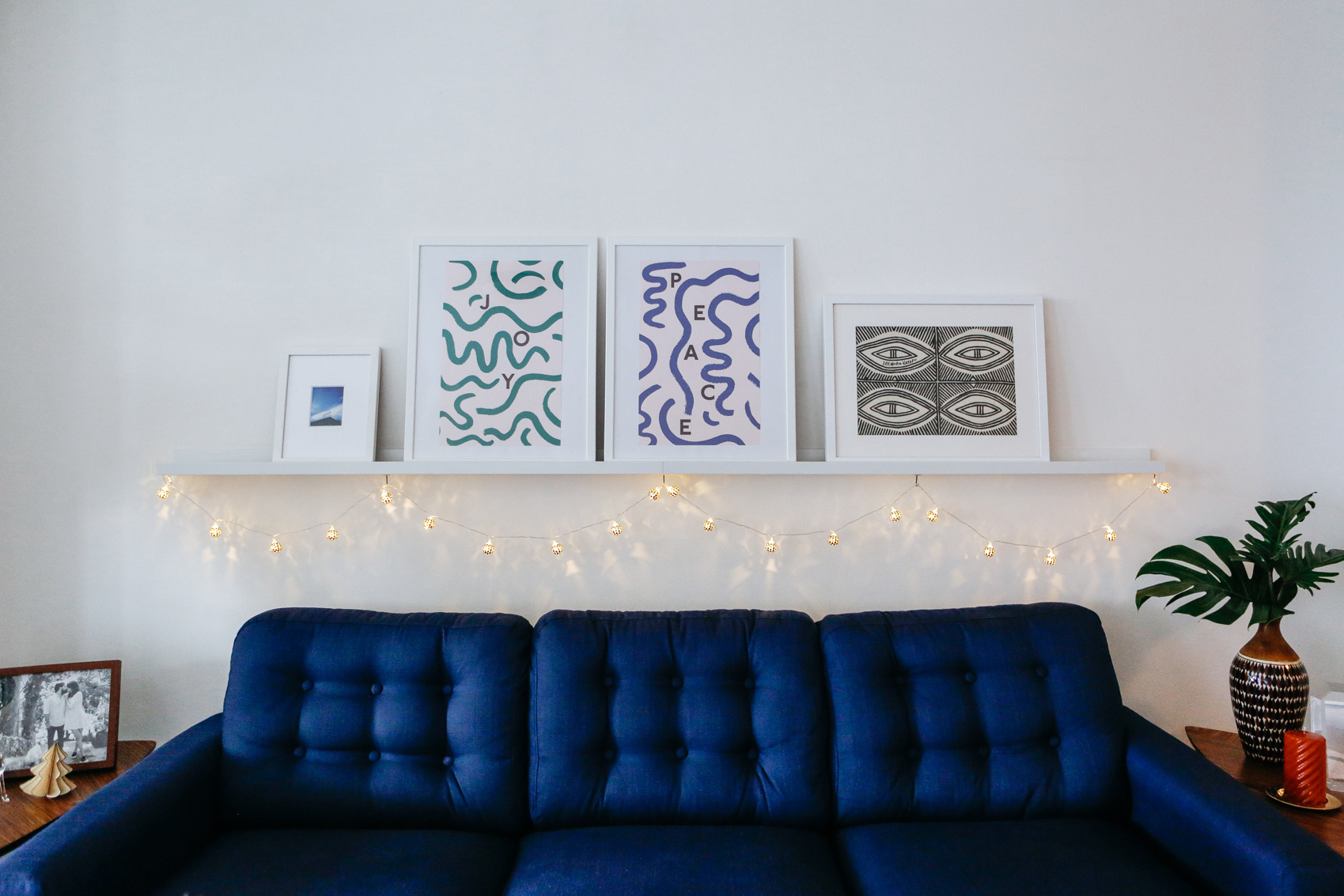 Shelf wall art and Christmas lights with blue sofa