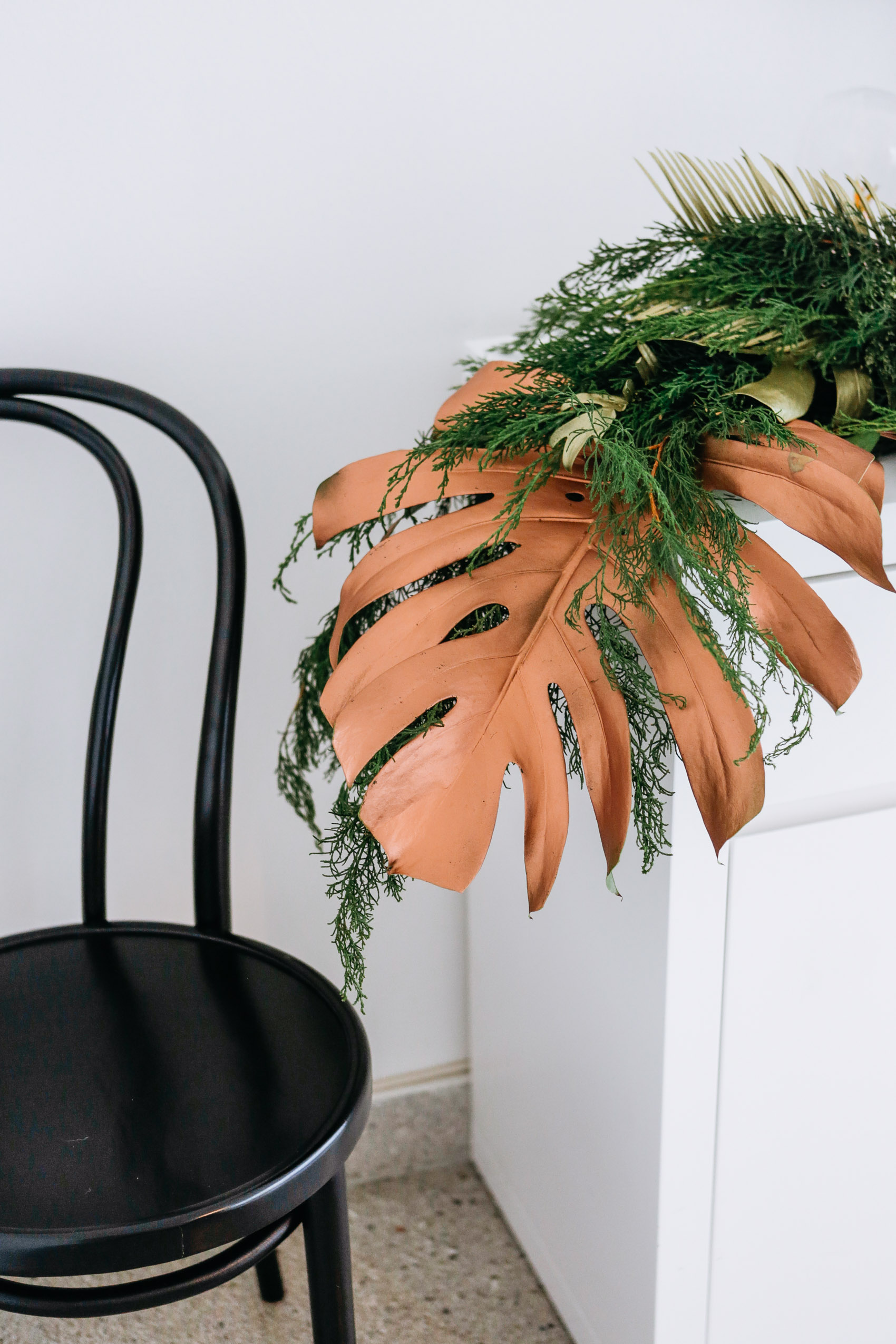 Rose gold painted monstera leaf holiday decoration with pine garland