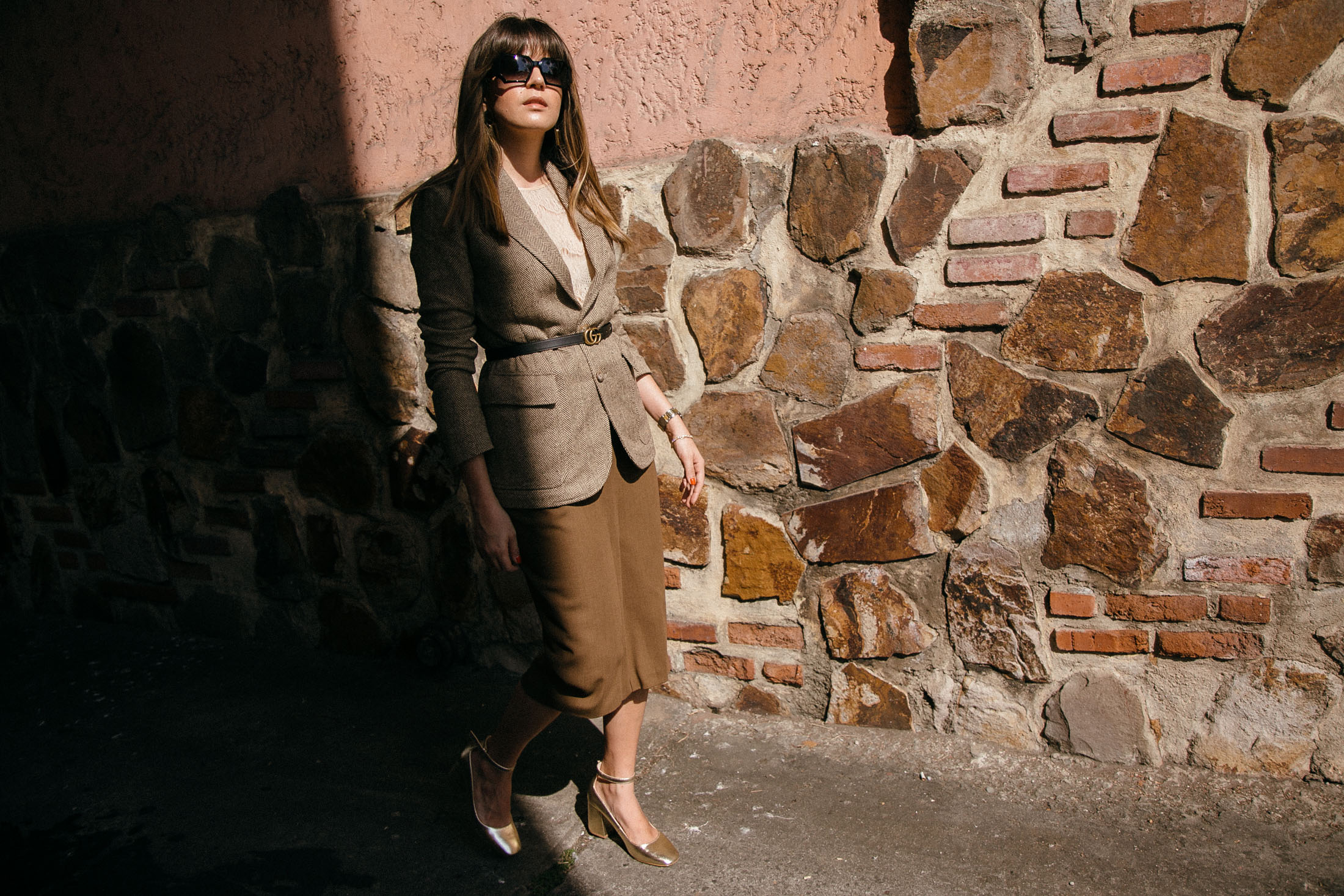 Maristella wears a belted blazer, pencil skirt, gold pumps and Chanel sunglasses