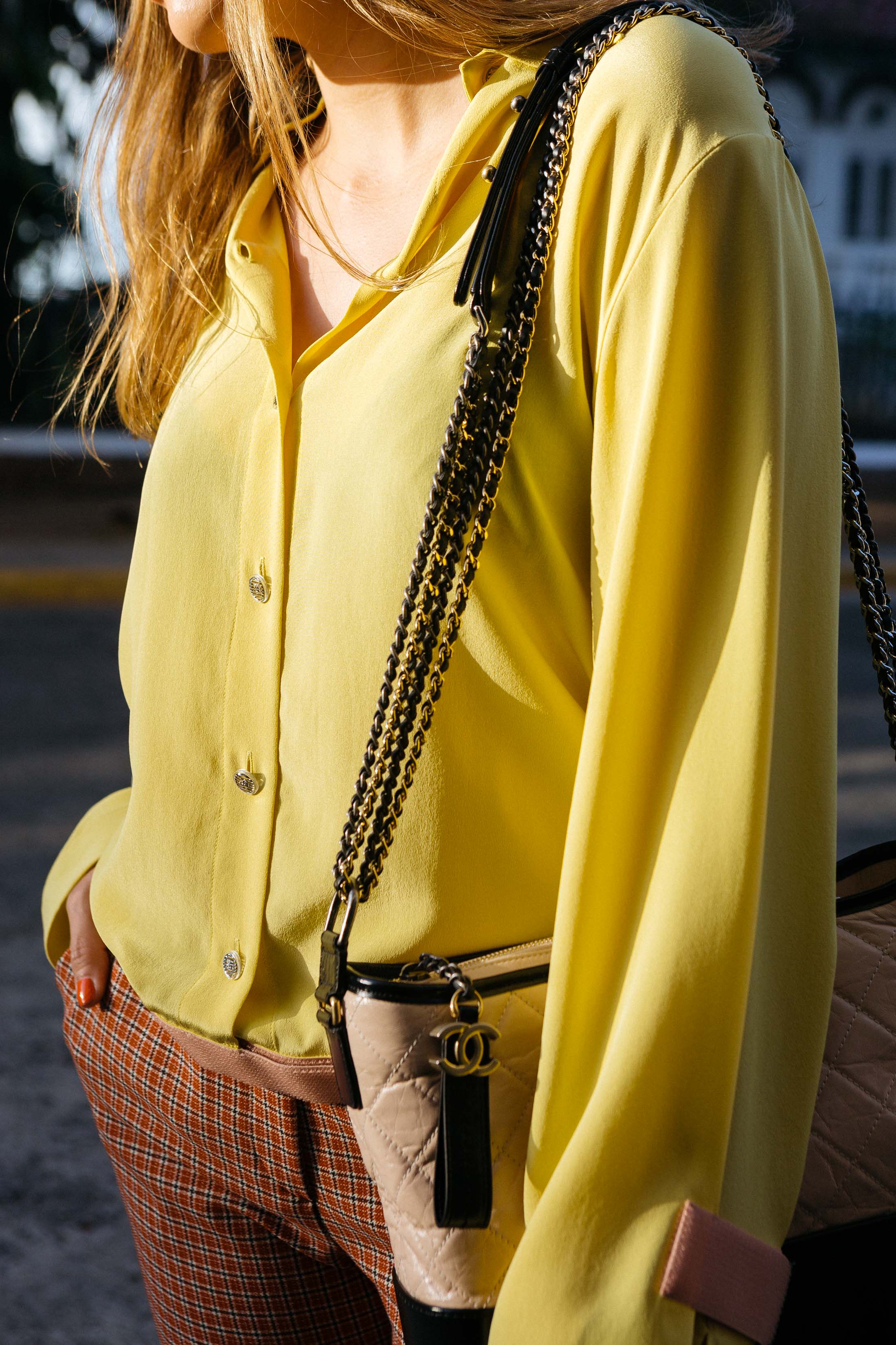 Outfit detail with Chanel Spring 2017 Data Center collection yellow silk blouse, plaid pants and Chanel Gabrielle bag in beige and black leather