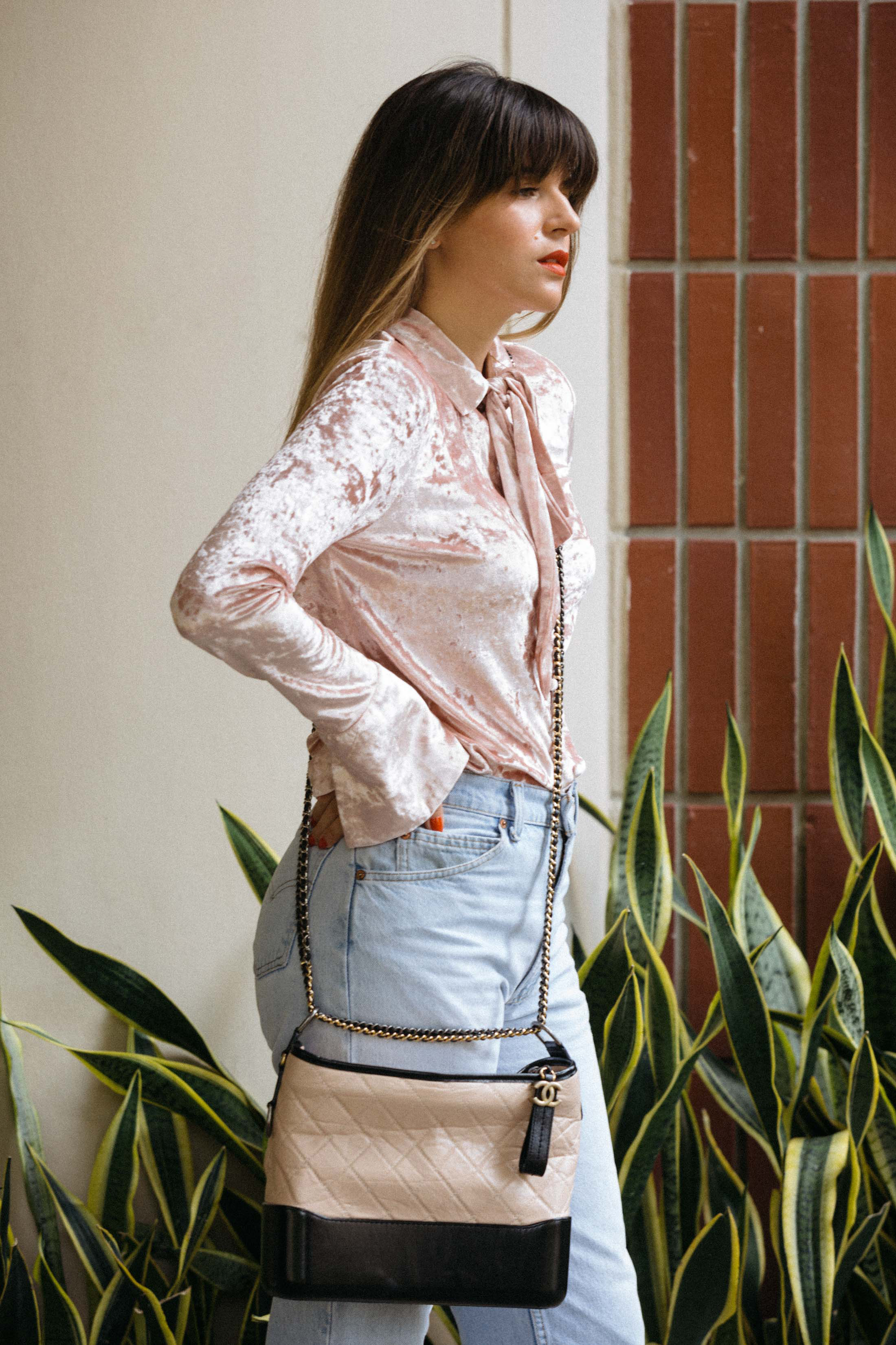 Maristella wears a pink velvet blouse, high rise jeans and Chanel cross body bag