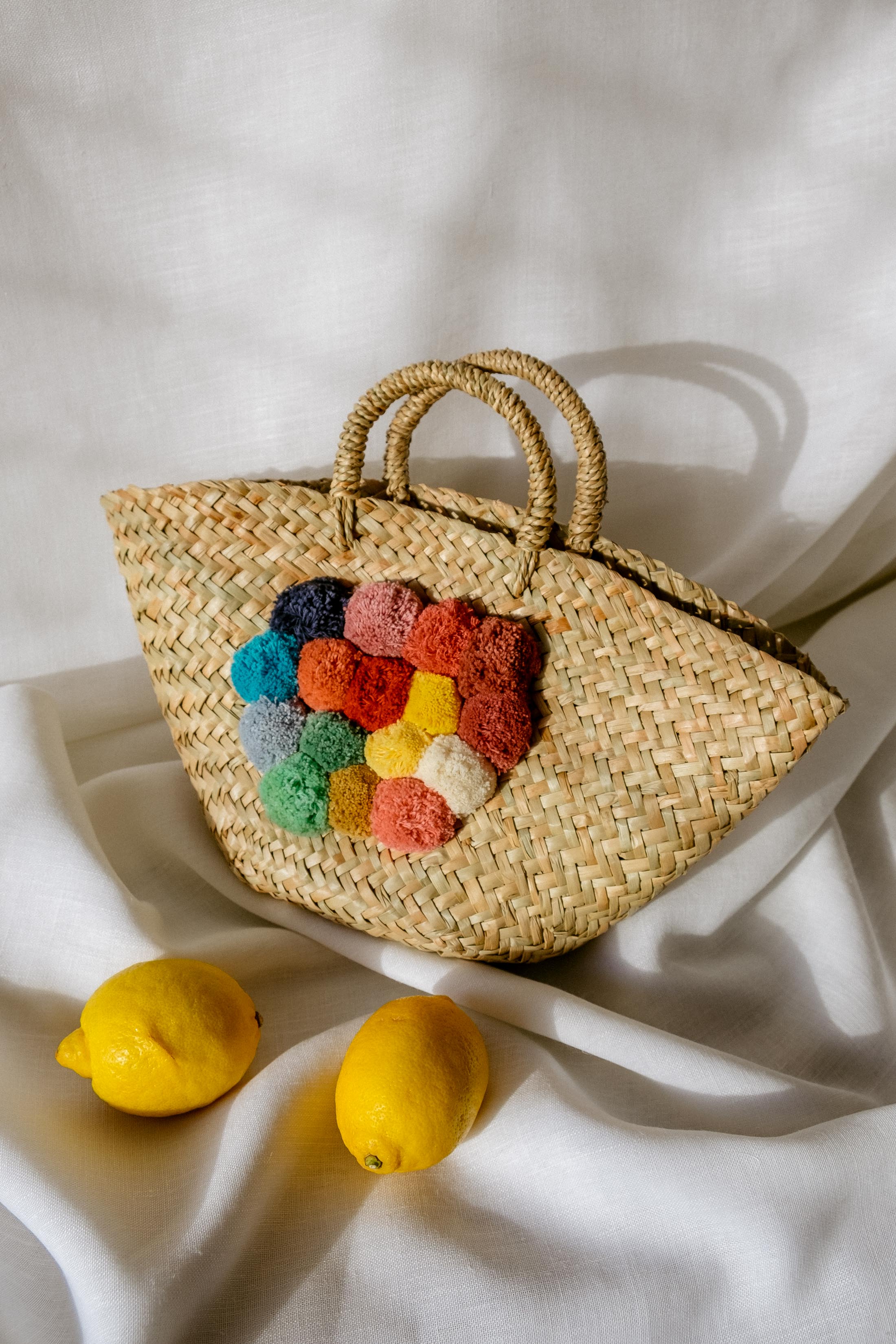 Straw bag with colorful poms by Purificación García