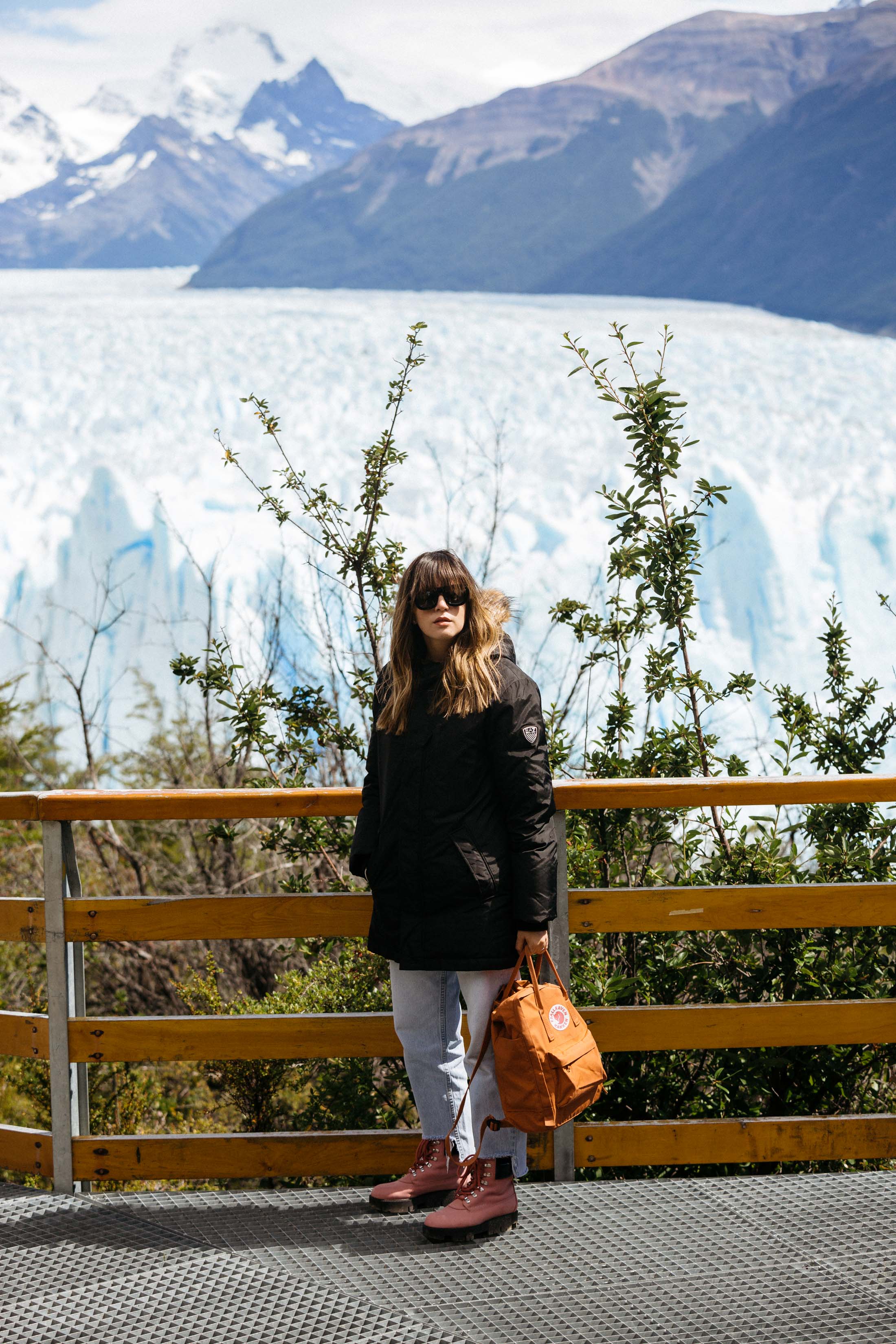 Maristella wears a black parka and pink Acne Telde boots at the Perito Moreno glacier in Patagonia