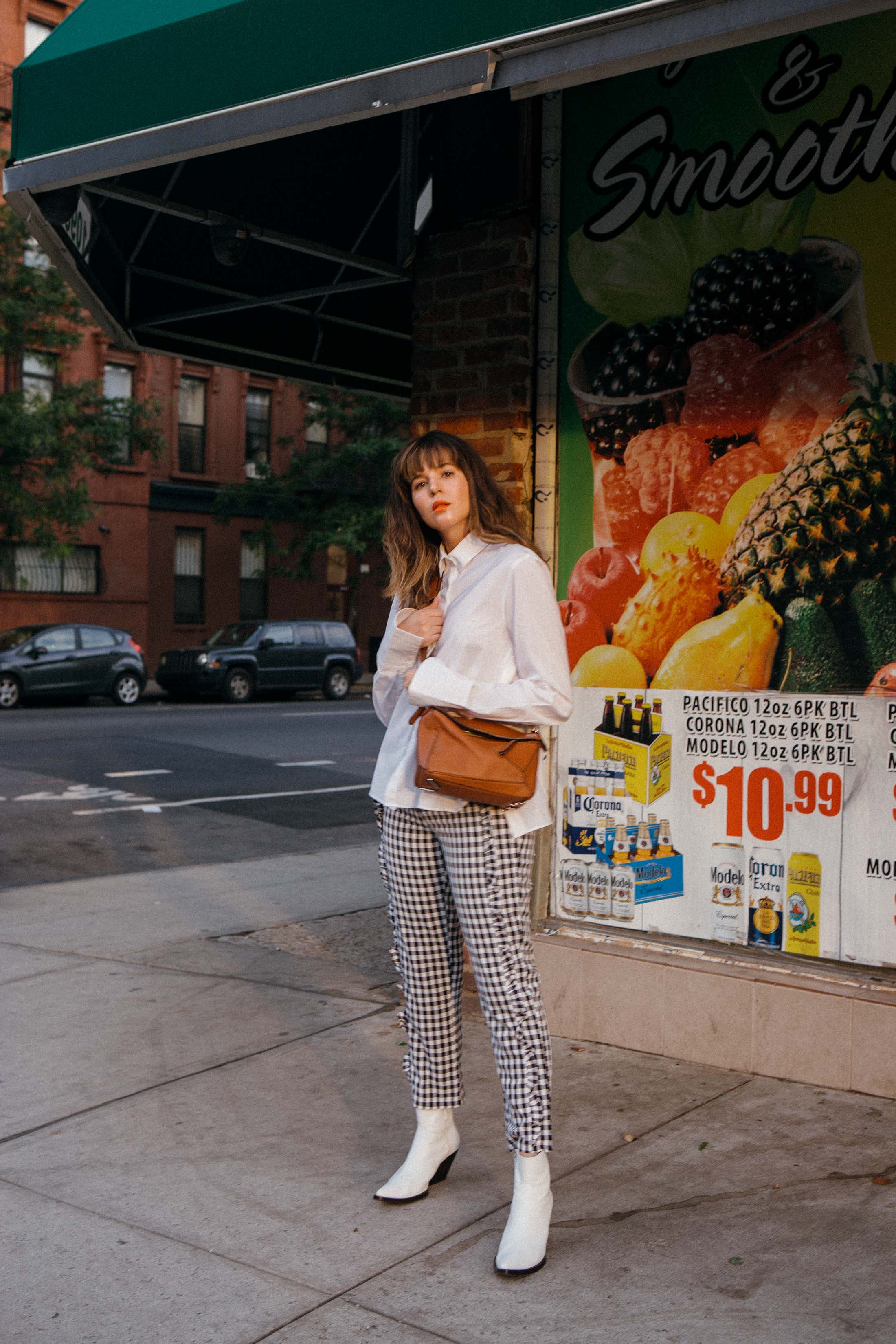 Maristella wears a white shirt, black gingham pants and white western style boots