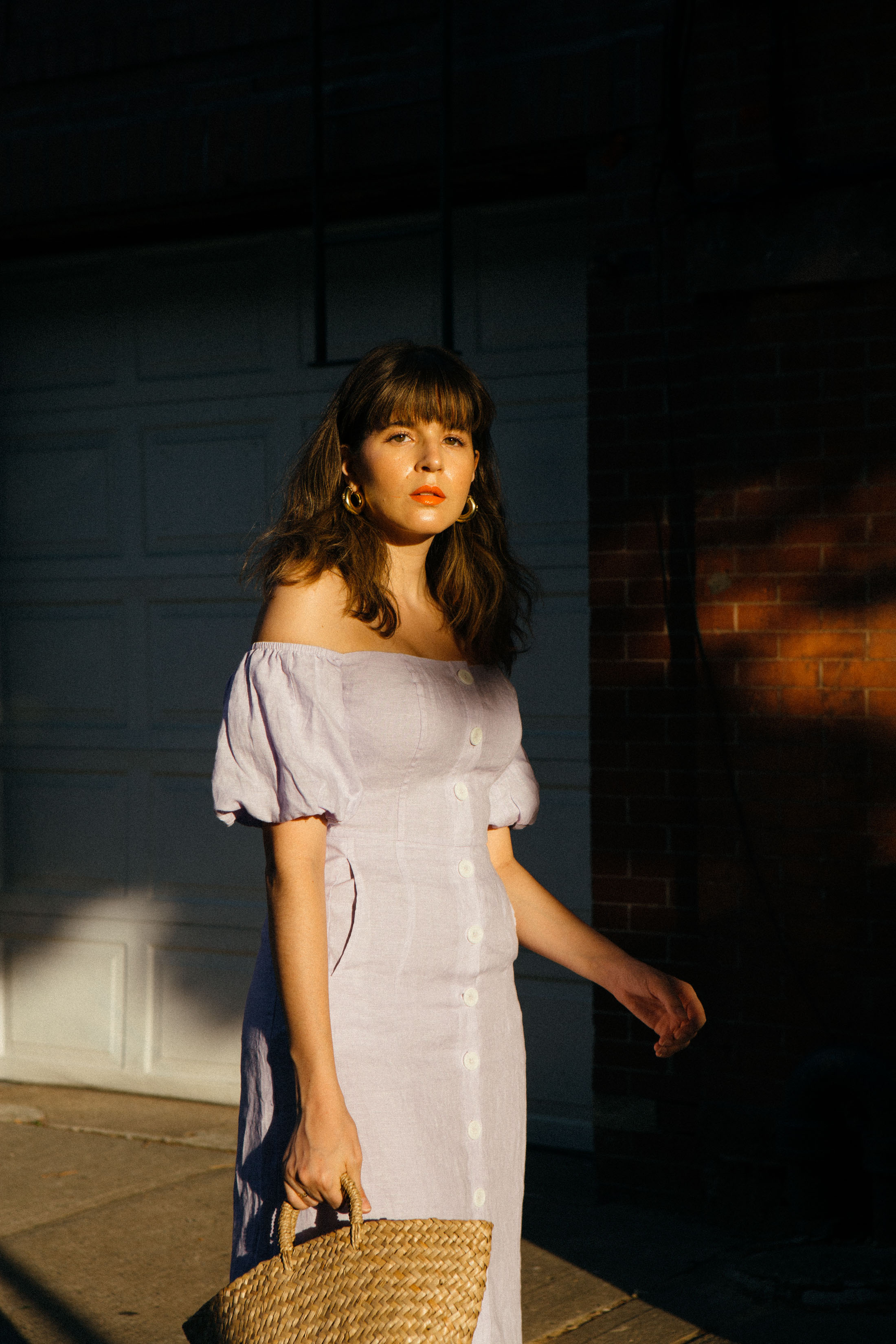 Maristella wears a button down off the shoulder dress in lilac linen