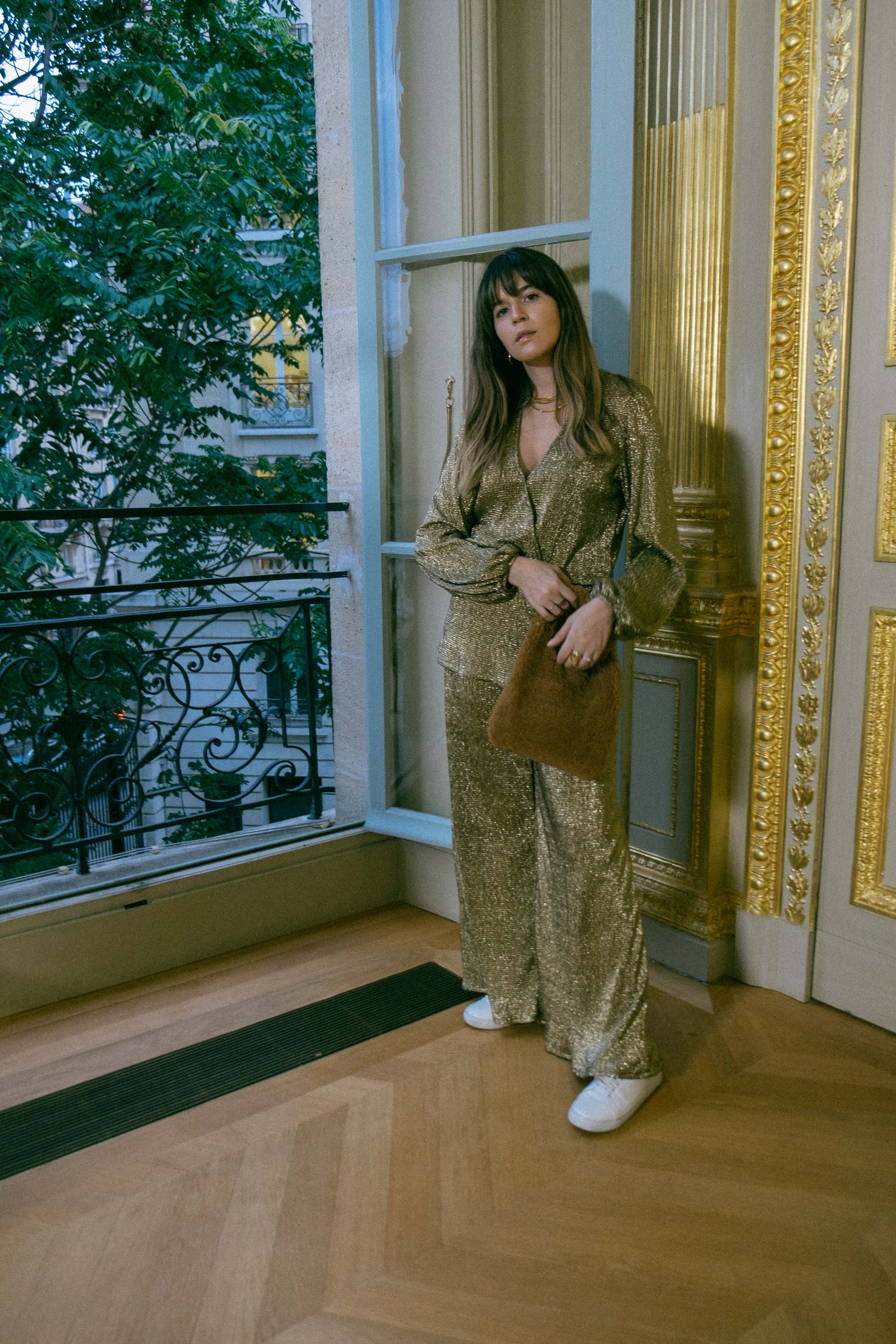 Maristella in a gold coordinated blouse and pants set with white sneakers and a teddy Loeffler Randall bag at the Ellery Presentation in Paris Fashion Week